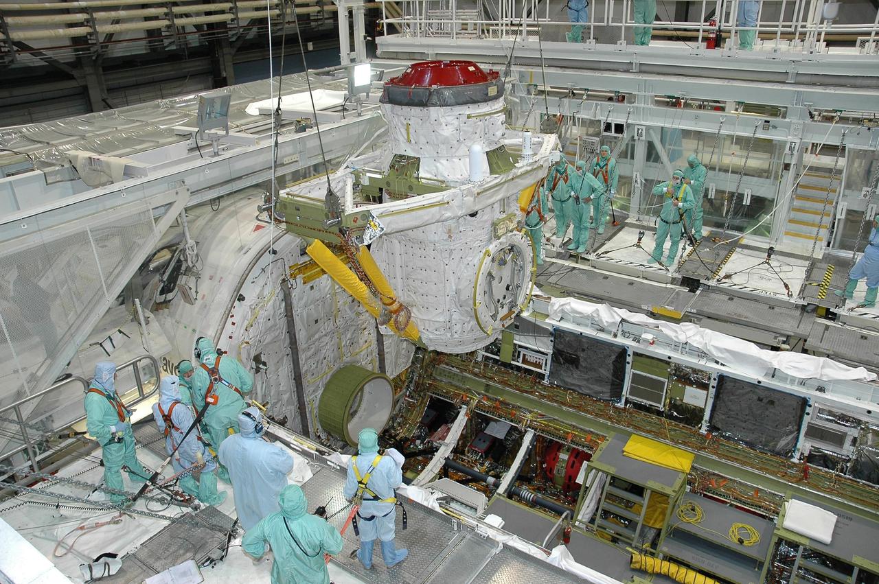 KENNEDY SPACE CENTER, FLA. - In Orbiter Processing Facility bay 2 at NASA's Kennedy Space Center, workers observe the movement of the airlock as it is lowered into Endeavour's payload bay for installation. The airlock is located in the middeck. The airlock and airlock hatches permit flight crew members to transfer from the middeck crew compartment into the payload bay for extravehicular activities in their space suits without depressurizing the orbiter crew cabin. The airlock is sized to accommodate two fully suited flight crew members simultaneously. Photo credit: NASA/Jim Grossmann