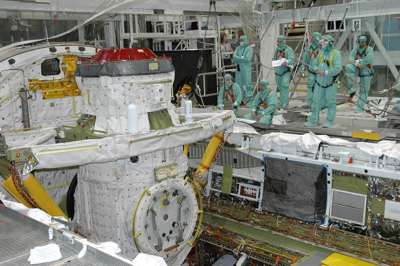 KENNEDY SPACE CENTER, FLA. - In Orbiter Processing Facility bay 2 at NASA's Kennedy Space Center, workers stand by as the airlock is lowered into place for installation into Endeavour's payload bay. The airlock is located in the middeck. The airlock and airlock hatches permit flight crew members to transfer from the middeck crew compartment into the payload bay for extravehicular activities in their space suits without depressurizing the orbiter crew cabin. The airlock is sized to accommodate two fully suited flight crew members simultaneously. Photo credit: NASA/Jim Grossmann