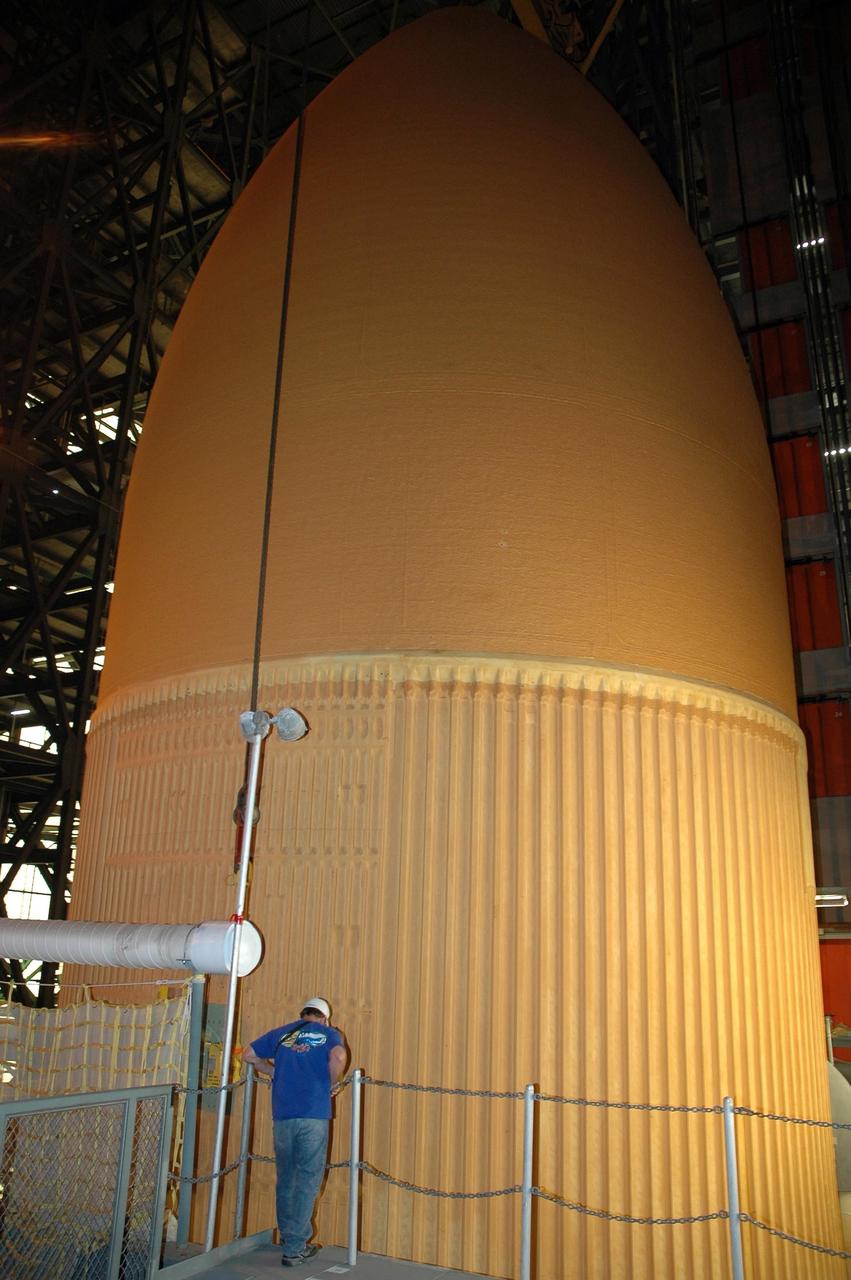 KENNEDY SPACE CENTER, FLA.  -  Inside the Vehicle Assembly Building at NASA's Kennedy Space Center, a worker watches external tank number 119 as it is being lifted from the checkout cell.  The tank will be placed horizontally on the transporter in the transfer aisle. Once in the transfer aisle, technicians will reapply the thermal protection system foam that was removed in order to replace the tank's four liquid hydrogen engine cutoff sensors. The tank is being prepared to launch Space Shuttle Discovery on mission STS-121 in July. Photo credit: NASA/Cory Huston