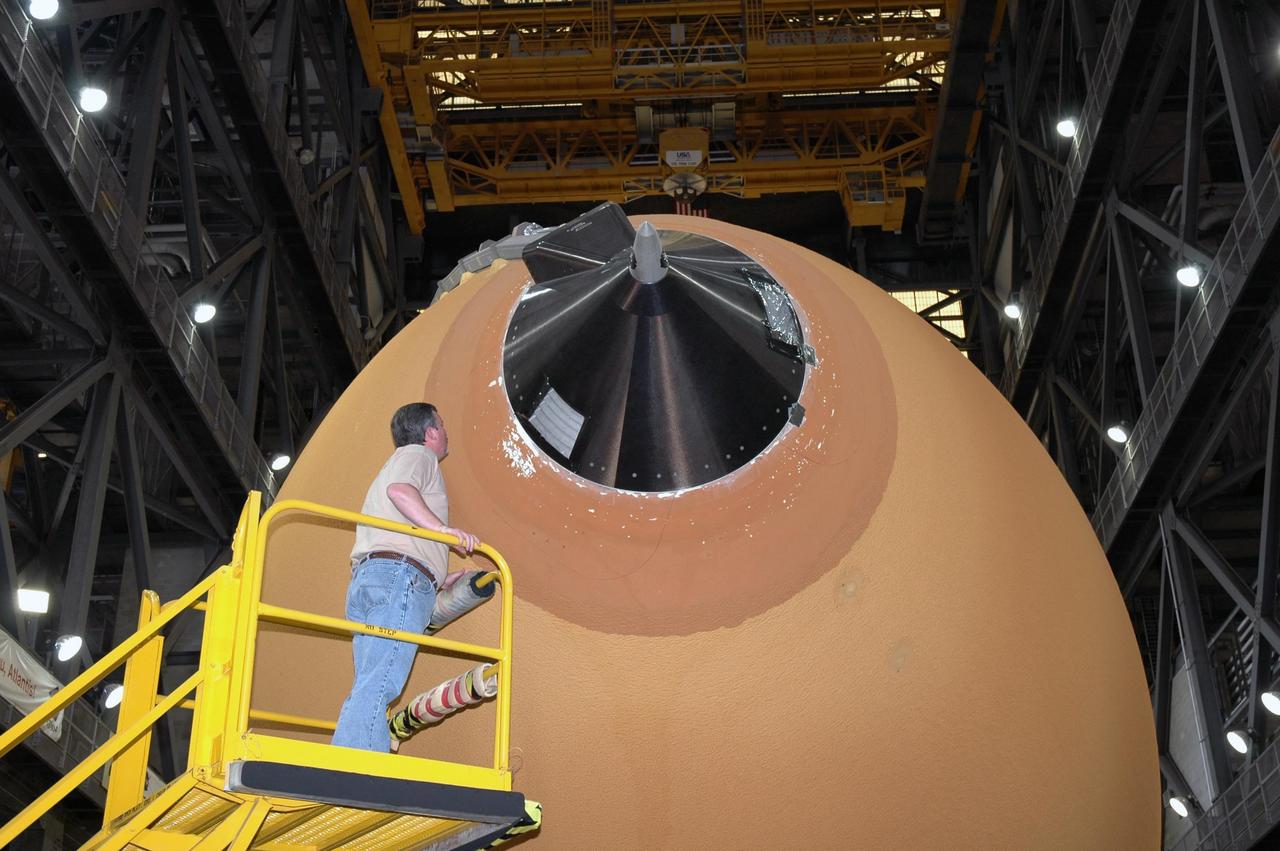 KENNEDY SPACE CENTER, FLA.  - In the transfer aisle of the Vehicle Assembly Building, a worker checks the top of the external tank where a new gaseous oxygen vent valve was installed under the nose cap of the tank.   The tank is being prepared to launch Space Shuttle Discovery on mission STS-121 in July.  Photo credit: NASA/Jim Grossmann