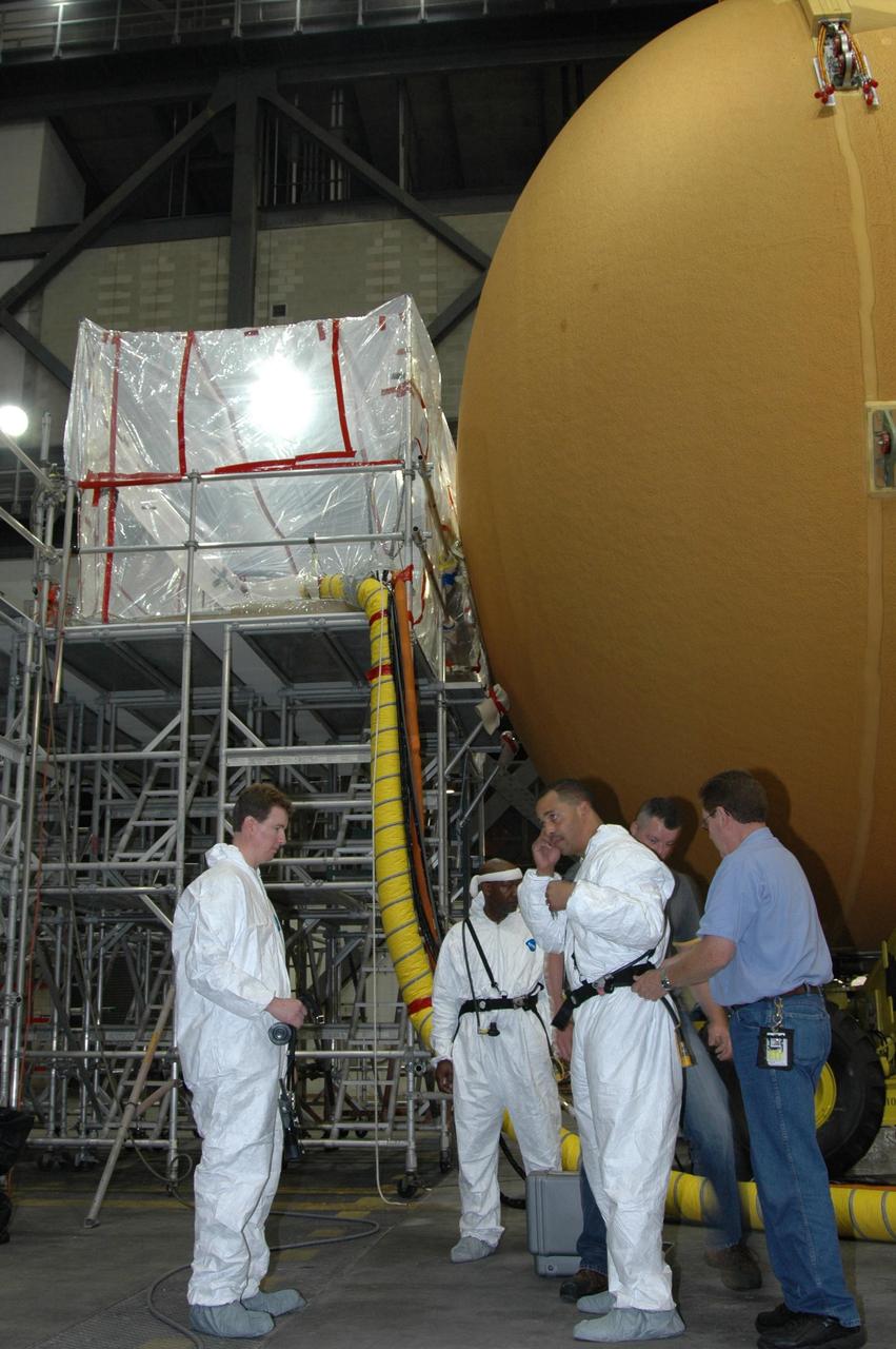 KENNEDY SPACE CENTER, FLA. -- Lockheed Martin technicians in the Vehicle Assembly Building at NASA's Kennedy Space Center prepare for the application of new foam over the manhole cover on the lower end of external tank No. 119. The manhole was removed to access the area where the tank's four liquid hydrogen engine cutoff sensors were replaced. Once reinstalled, the manhole required new foam to be applied. The tank is being prepared to launch Space Shuttle Discovery on mission STS-121 in July. Photo credit: NASA/Jim Grossmann