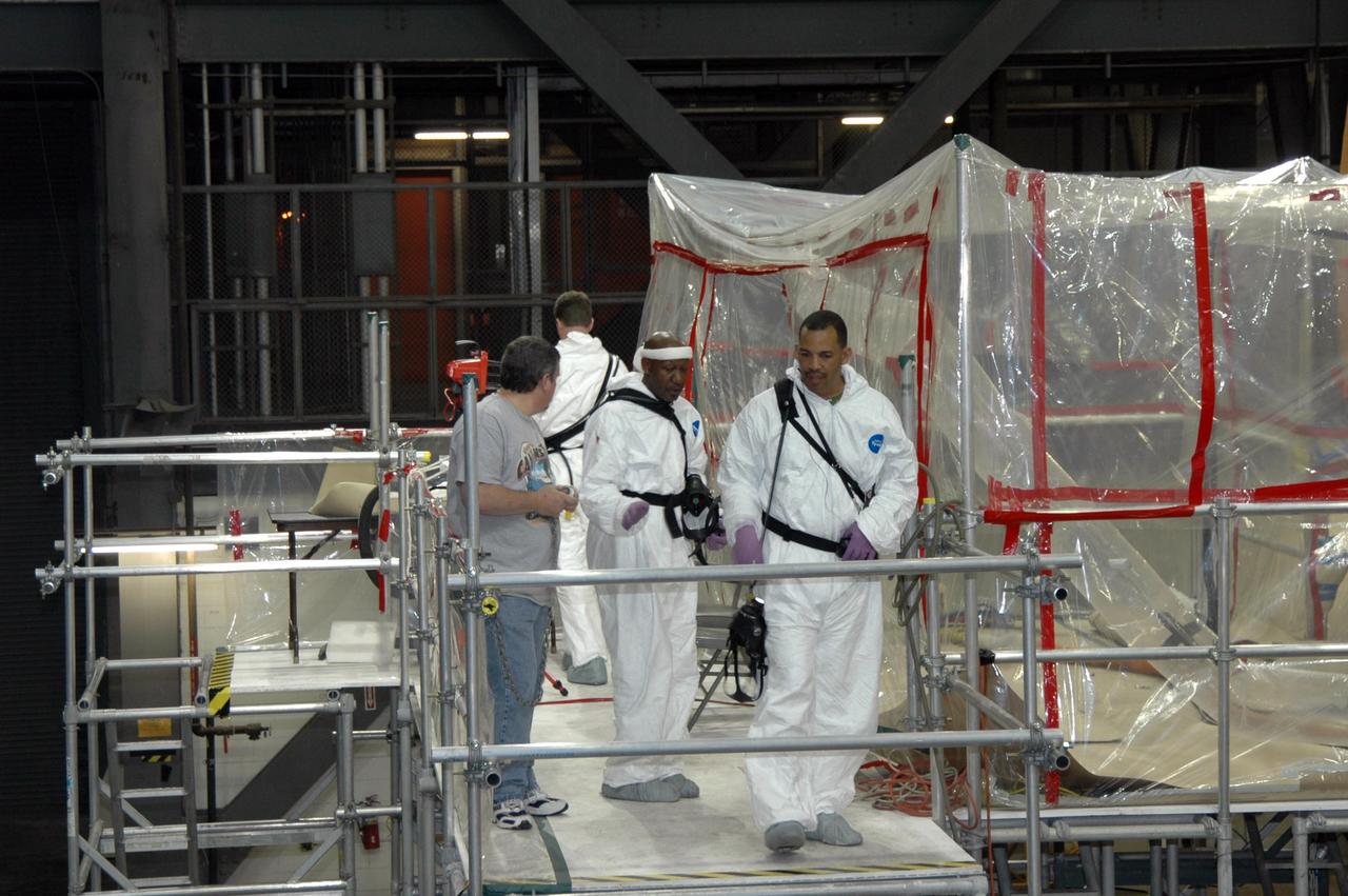 KENNEDY SPACE CENTER, FLA. -- Lockheed Martin technicians in the Vehicle Assembly Building at NASA's Kennedy Space Center prepare for the application of new foam over the manhole cover on the lower end of external tank No. 119. The manhole was removed to access the area where the tank's four liquid hydrogen engine cutoff sensors were replaced. Once reinstalled, the manhole required new foam to be applied. The tank is being prepared to launch Space Shuttle Discovery on mission STS-121 in July. Photo credit: NASA/Jim Grossmann