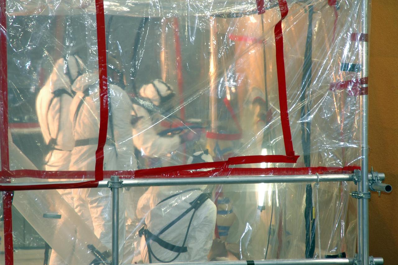 KENNEDY SPACE CENTER, FLA. -- Lockheed Martin technicians in the Vehicle Assembly Building at NASA's Kennedy Space Center apply new foam over the manhole cover on the lower end of external tank No. 119. The manhole was removed to access the area where the tank's four liquid hydrogen engine cutoff sensors were replaced. Once reinstalled, the manhole required new foam to be applied. The tank is being prepared to launch Space Shuttle Discovery on mission STS-121 in July. Photo credit: NASA/Jim Grossmann
