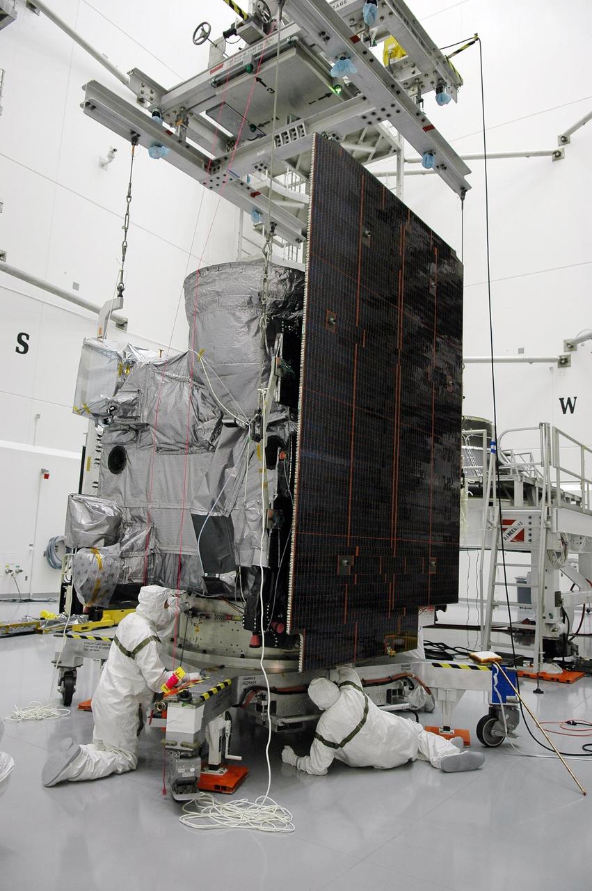 KENNEDY SPACE CENTER, FLA. - Inside a high bay at Astrotech Space Operations in Titusville, Fla., the GOES-N spacecraft, workers secure the lines to an overhead crane. The spacecraft will be lifted and moved for mating with its payload adapter. GOES-N is the latest in a series of Geostationary Operational Environmental Satellites for NOAA and NASA providing continuous monitoring necessary for intensive data analysis. It will be launched May 18 on a Boeing Delta IV rocket from Cape Canaveral Air Force Station in Florida. Photo credit: NASA/Kim Shiflett
