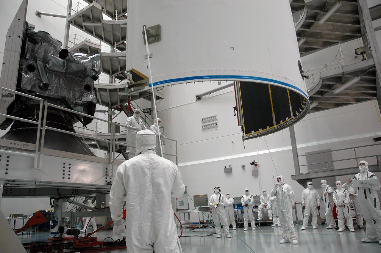 KENNEDY SPACE CENTER, FLA. - In the high bay at Astrotech Space Operations in Titusville, Fla., workers help guide the first half of the fairing toward the GOES-N spacecraft. The fairing will be used to encapsulate, or enclose, the GOES-N satellite for launch. The fairing protects the spacecraft during launch and flight through the atmosphere. Once out of the atmosphere, the fairing is jettisoned. GOES-N is the latest in a series of Geostationary Operational Environmental Satellites for NOAA and NASA providing continuous monitoring necessary for intensive data analysis. GOES-N will be launched May 18 on a Boeing Delta IV rocket from Cape Canaveral Air Force Station in Florida. Photo credit: NASA/Jack Pfaller