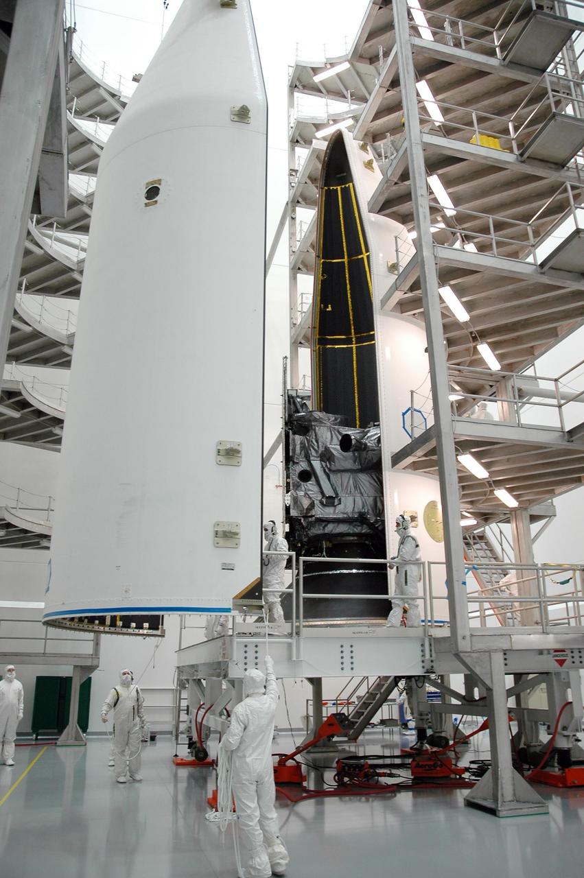 KENNEDY SPACE CENTER, FLA. - In the high bay at Astrotech Space Operations in Titusville, Fla., workers help guide the second half of the fairing toward the GOES-N spacecraft. When both halves are in place, they will encapsulate, or enclose, the GOES-N satellite for launch. The fairing protects the spacecraft during launch and flight through the atmosphere. Once out of the atmosphere, the fairing is jettisoned. GOES-N is the latest in a series of Geostationary Operational Environmental Satellites for NOAA and NASA providing continuous monitoring necessary for intensive data analysis. GOES-N will be launched May 18 on a Boeing Delta IV rocket from Cape Canaveral Air Force Station in Florida. Photo credit: NASA/Jack Pfaller