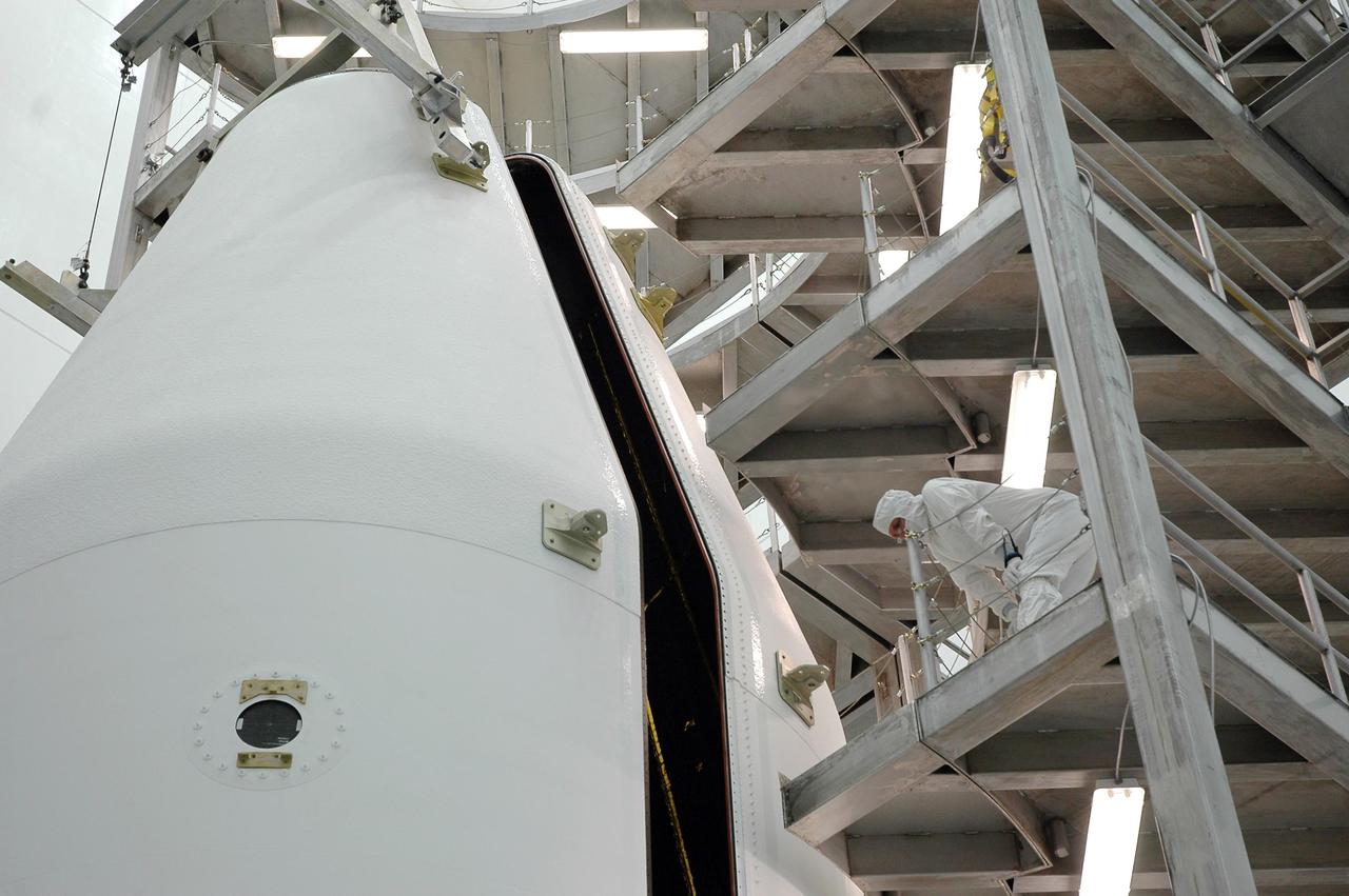 KENNEDY SPACE CENTER, FLA. - From a vantage point high on a work platform in the high bay at Astrotech Space Operations in Titusville, Fla., a worker checks the progress of the movement of the fairing halves as they enclose the GOES-N satellite. The fairing protects the spacecraft during launch and flight through the atmosphere. Once out of the atmosphere, the fairing is jettisoned. GOES-N is the latest in a series of Geostationary Operational Environmental Satellites for NOAA and NASA providing continuous monitoring necessary for intensive data analysis. GOES-N will be launched May 18 on a Boeing Delta IV rocket from Cape Canaveral Air Force Station in Florida. Photo credit: NASA/Jack Pfaller