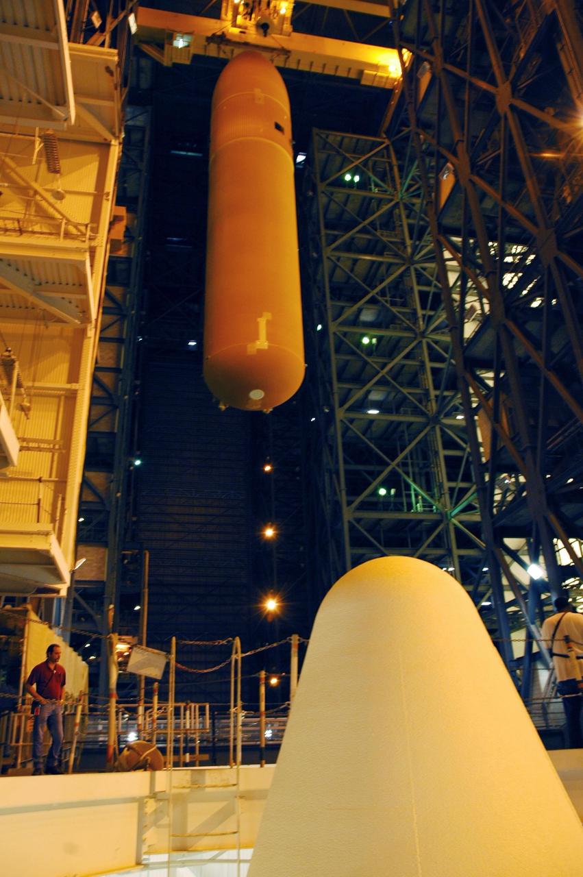 KENNEDY SPACE CENTER, FLA.  -  In the Vehicle Assembly Building, the overhead crane moves the external tank designated for Space Shuttle Discovery toward high bay 3.  In the foreground is the tip of one of the solid rocket boosters. There it will be stacked with the solid rocket boosters already in place on the mobile launcher platform.  Discovery is scheduled to launch on mission STS-121 in July.  Photo credit: NASA/Amanda Diller