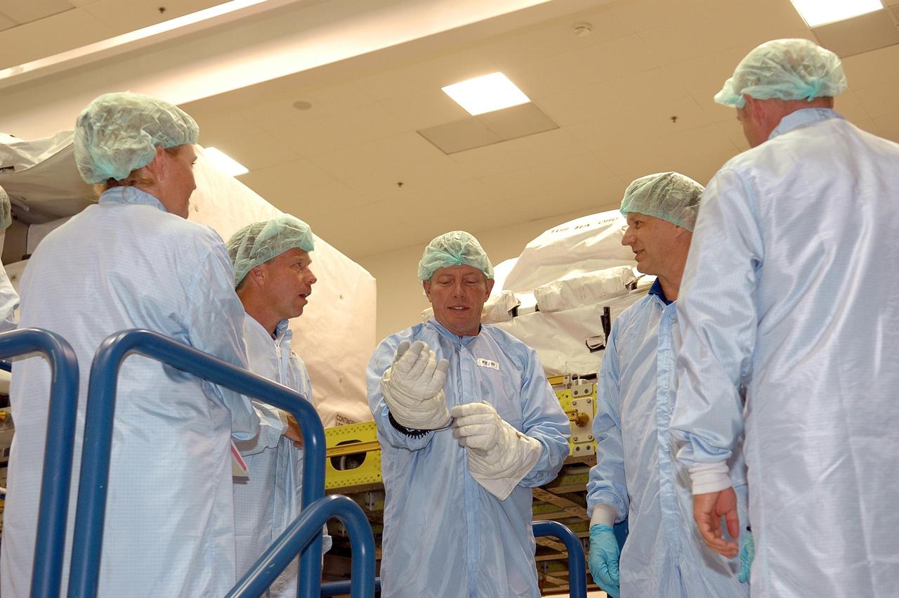 KENNEDY SPACE CENTER, FLA.  -  While STS-121 Mission Specialist Michael Fossum (center) fixes his glove, Commander Steven Lindsey (left) and Mission Specialist Piers Sellers (right) talk about their next step in the Crew Equipment Interface Test at the SPACEHAB facility in Cape Canaveral. This test allows the astronauts to become familiar with equipment they will be using on their upcoming mission. STS-121 is scheduled to launch in July aboard Space Shuttle Discovery. Photo credit: NASA/Kim Shiflett