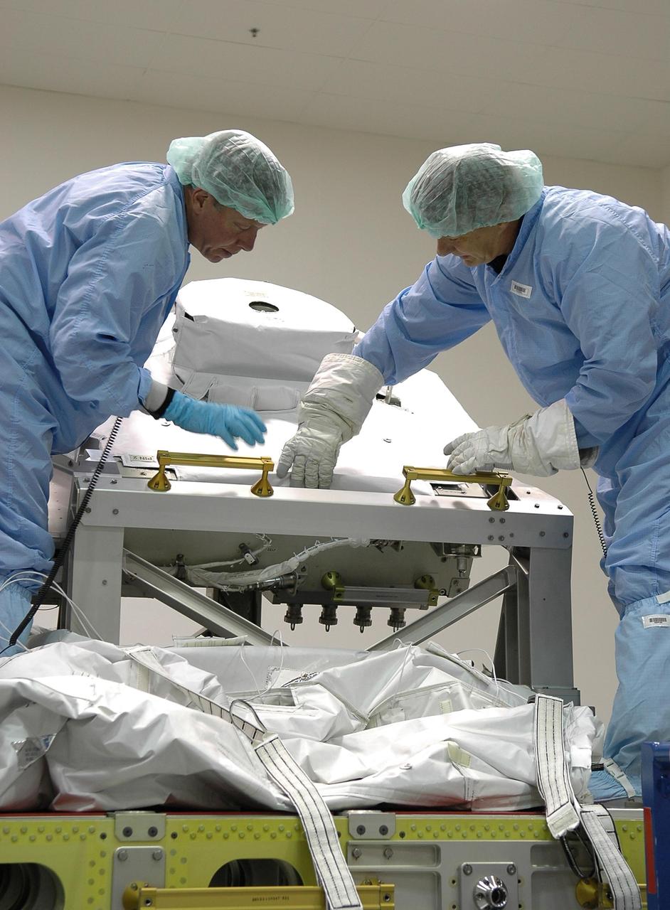 KENNEDY SPACE CENTER, FLA.  -  STS-121 Commander Steven Lindsey  (left) and Mission Specialist Piers Sellers (right) are removing a cover on the trailing umbilical assembly at the SPACEHAB facility in Cape Canaveral during a Crew Equipment Interface Test. This test allows the astronauts to become familiar with equipment they will be using on their upcoming mission. STS-121 is scheduled to launch in July aboard Space Shuttle Discovery.  Photo credit: NASA/Kim Shiflett