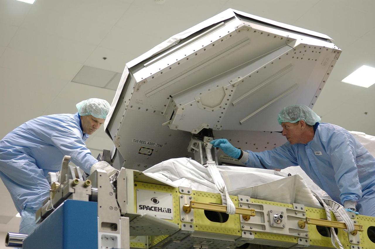 KENNEDY SPACE CENTER, FLA.  -  STS-121 Mission Specialist Piers Sellers (left)  and Commander Steven Lindsey (right) are practicing removing the cover and strap on the trailing umbilical assembly at the SPACEHAB facility in Cape Canaveral during a Crew Equipment Interface Test. This test allows the astronauts to become familiar with equipment they will be using on their upcoming mission. STS-121 is scheduled to launch in July aboard Space Shuttle Discovery.  Photo credit: NASA/Kim Shiflett