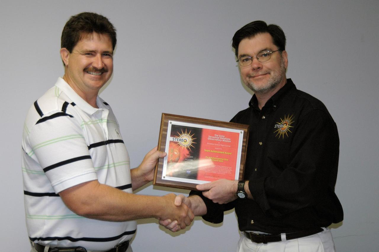 KENNEDY SPACE CENTER, FLA. - Jim Adams (right), deputy project manager for NASA's Solar Terrestrial Relations Observatory (STEREO), Goddard Space Flight Center, presents a certificate of appreciation to Dwayne Light, director of Florida Operations, Astrotech, a payload processing facility near Kennedy Space Center. The occasion was the ribbon-cutting for a clean-room enclosure, within the high bay at Astrotech. The enclosure meets the additional stringent cleanliness requirements necessary for processing STEREO for launch. It was designed and constructed by Astrotech to meet the spacecraft requirements provided by STEREO project management at NASA's Goddard Space Flight Center, Greenbelt, Md. STEREO consists of two spacecraft whose mission is the first to take measurements of the sun and solar wind in 3-D. Launch aboard a Boeing Delta II rocket from Launch Complex 17 on Cape Canaveral Air Force Station is scheduled to occur over the summer. Photo credit: NASA/Dimitri Gerondidakis