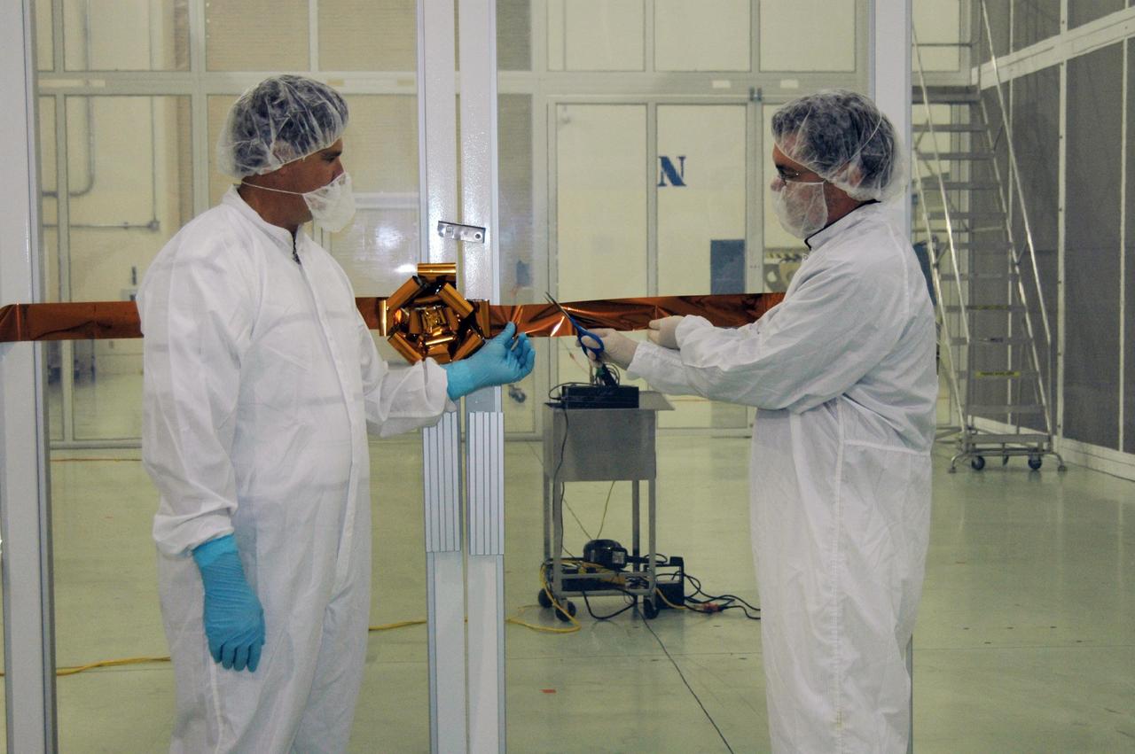 KENNEDY SPACE CENTER, FLA. - Dwayne Light (left), director of Florida Operations, Astrotech, assists Jim Adams, deputy project manager for NASA's Solar Terrestrial Relations Observatory (STEREO), Goddard Space Flight Center, as he cuts the ribbon to officially open the new class 10,000 clean-room enclosure at Astrotech, a payload processing facility near Kennedy Space Center. This clean-room enclosure, within the high bay at Astrotech, meets the additional stringent cleanliness requirements necessary for processing STEREO for launch.  The enclosure was designed and constructed by Astrotech to meet the spacecraft requirements provided by STEREO project management at NASA's Goddard Space Flight Center, Greenbelt, Md. STEREO consists of two spacecraft whose mission is the first to take measurements of the sun and solar wind in 3-D. Launch aboard a Boeing Delta II rocket from Launch Complex 17 on Cape Canaveral Air Force Station is scheduled to occur over the summer. Photo credit: NASA/Dimitri Gerondidakis
