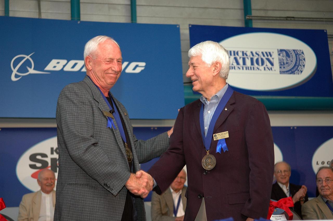 KENNEDY SPACE CENTER, FLA. - Henry "Hank" Hartsfield Jr. (right) accepts congratulations from Al Worden, U.S. Astronaut Hall of Fame member and chairman of the Astronaut Scholarship Foundation. The occasion is the 2006 induction ceremony for the U.S. Astronaut Hall of Fame, held in the Apollo/Saturn V Center. The inductees for 2006 are former NASA astronauts Hartsfield, Brewster H. Shaw Jr. and Charles F. Bolden Jr. Hartsfield flew on three space shuttle missions including STS-4, STS-41D and STS-61A, logging 482 hours in space. The U.S. Astronaut Hall of Fame now includes 63 space explorers. Photo credit: NASA/Kim Shiflett