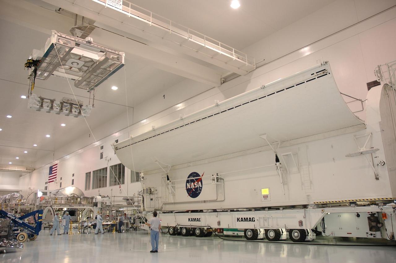 KENNEDY SPACE CENTER, FLA. - In the Space Station Processing Facility, a crane moves the Lightweight Multi-Purpose Experiment Support Structure Carrier (LMC) toward a payload canister, doors open to receive it. Slated to fly on space shuttle mission STS-121, the LMC is ready to be delivered to Launch Pad 39B for installation into orbiter Discovery. It is a cross-bay carrier for hardware required to perform development test objective 848. Test objective 848 is a demonstration of the tools and techniques developed to repair damaged orbiter thermal protection system tiles during a spacewalk, or extravehicular activity. The target launch window for STS-121 is July 1 to July 19, 2006. Photo credit: NASA/Cory Husten