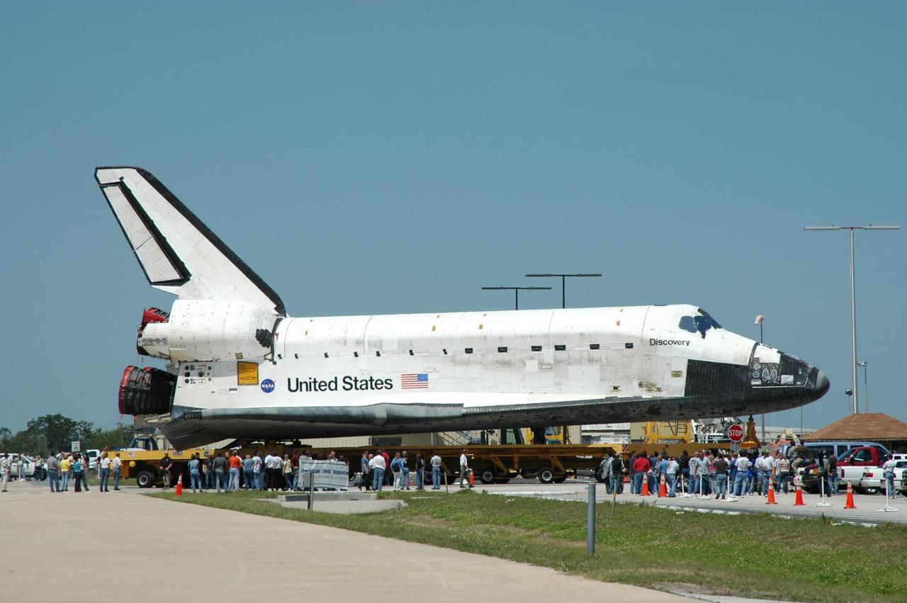 KENNEDY SPACE CENTER, FLA. - Workers crowd around the orbiter Discovery, sitting on an orbiter transporter, as it glides out of NASA's Orbiter Processing Facility to begin the rollover to the Vehicle Assembly Building (VAB). The rollover marks the start of the journey to the launch pad and, ultimately, launch. Once inside the VAB, Discovery will be raised to vertical and lifted up and over into high bay 3 for stacking with its redesigned external tank and twin solid rocket boosters. The rollout of Space Shuttle Discovery to Launch Pad 39B is expected in approximately a week. Launch of Discovery on mission STS-121 is scheduled to take place in a window extending July 1 to July 19. Photo credit: NASA/Jim Grossmann