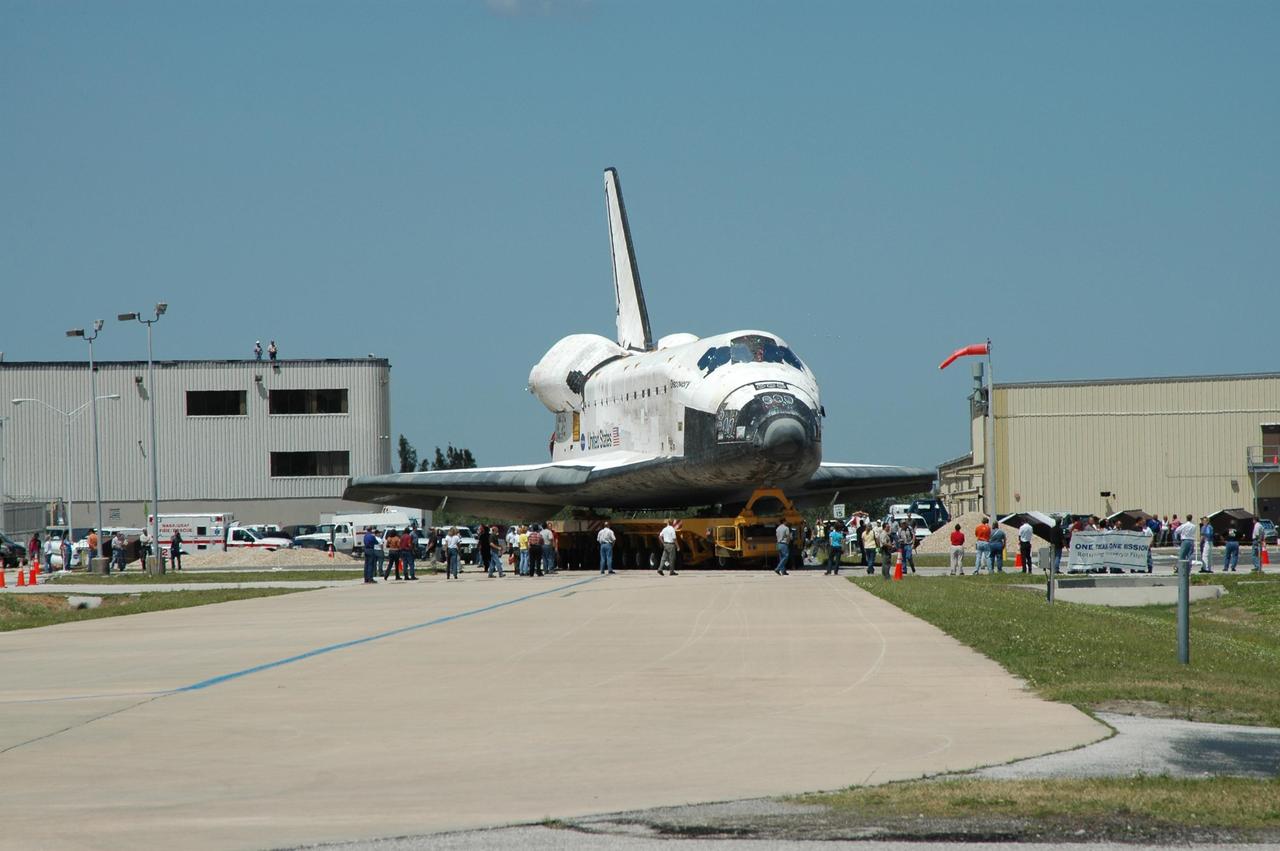 KENNEDY SPACE CENTER, FLA. - The orbiter Discovery, sitting on an orbiter transporter, turns the corner after gliding out of NASA's Orbiter Processing Facility to begin the rollover to the Vehicle Assembly Building (VAB). The rollover marks the start of the journey to the launch pad and, ultimately, launch. Once inside the VAB, Discovery will be raised to vertical and lifted up and over into high bay 3 for stacking with its redesigned external tank and twin solid rocket boosters. The rollout of Space Shuttle Discovery to Launch Pad 39B is expected in approximately a week. Launch of Discovery on mission STS-121 is scheduled to take place in a window extending July 1 to July 19. Photo credit: NASA/Jim Grossmann