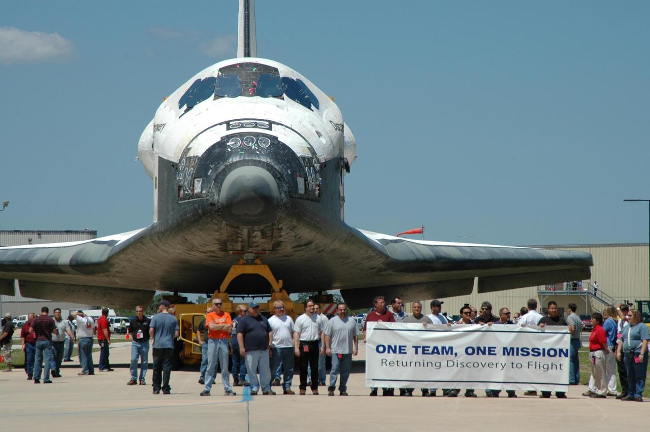 KENNEDY SPACE CENTER, FLA. - As the orbiter Discovery, sitting on an orbiter transporter, moves away from NASA's Orbiter Processing Facility toward the Vehicle Assembly Building (VAB), workers accompany the vehicle. The rollover to the VAB marks the start of the journey to the launch pad and, ultimately, launch. Once inside the VAB, Discovery will be raised to vertical and lifted up and over into high bay 3 for stacking with its redesigned external tank and twin solid rocket boosters. The rollout of Space Shuttle Discovery to Launch Pad 39B is expected in approximately a week. Launch of Discovery on mission STS-121 is scheduled to take place in a window extending July 1 to July 19. Photo credit: NASA/Jim Grossmann