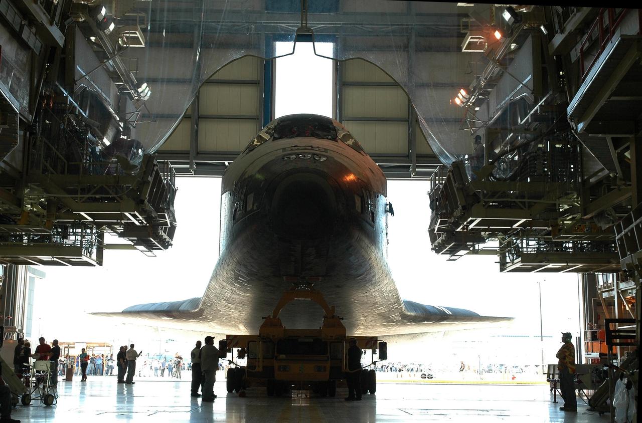 KENNEDY SPACE CENTER, FLA. - The orbiter Discovery, sitting on an orbiter transporter, slowly backs out of NASA's Orbiter Processing Facility to begin the rollover to the Vehicle Assembly Building (VAB). The rollover marks the start of the journey to the launch pad and, ultimately, launch. Once inside the VAB, Discovery will be raised to vertical and lifted up and over into high bay 3 for stacking with its redesigned external tank and twin solid rocket boosters. The rollout of Space Shuttle Discovery to Launch Pad 39B is expected in approximately a week. Launch of Discovery on mission STS-121 is scheduled to take place in a window extending July 1 to July 19. Photo credit: NASA/Jack Pfaller