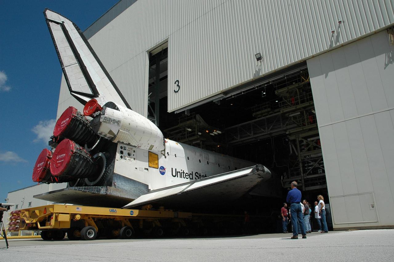 KENNEDY SPACE CENTER, FLA. - The orbiter Discovery, sitting on an orbiter transporter, slowly backs out of NASA's Orbiter Processing Facility to begin the rollover to the Vehicle Assembly Building (VAB). The rollover marks the start of the journey to the launch pad and, ultimately, launch. Once inside the VAB, Discovery will be raised to vertical and lifted up and over into high bay 3 for stacking with its redesigned external tank and twin solid rocket boosters. The rollout of Space Shuttle Discovery to Launch Pad 39B is expected in approximately a week. Launch of Discovery on mission STS-121 is scheduled to take place in a window extending July 1 to July 19. Photo credit: NASA/Jack Pfaller