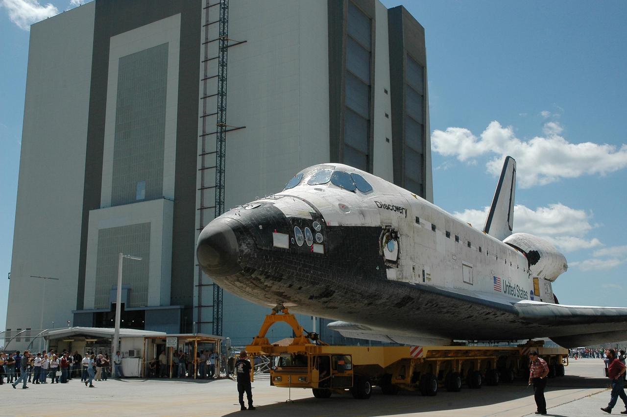 KENNEDY SPACE CENTER, FLA. - The orbiter Discovery, sitting on an orbiter transporter, begins making the short trip to NASA's Vehicle Assembly Building (VAB) , seen behind it. The rollover marks the start of the journey to the launch pad and, ultimately, launch. Once inside the VAB, Discovery will be raised to vertical and lifted up and over into high bay 3 for stacking with its redesigned external tank and twin solid rocket boosters. The rollout of Space Shuttle Discovery to Launch Pad 39B is expected in approximately a week. Launch of Discovery on mission STS-121 is scheduled to take place in a window extending July 1 to July 19. Photo credit: NASA/Jack Pfaller
