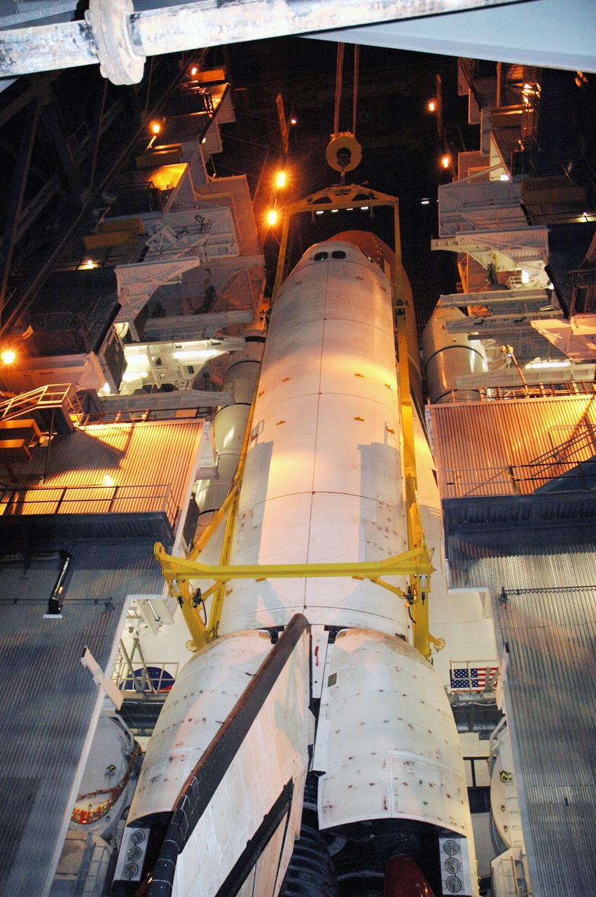 KENNEDY SPACE CENTER, FLA. -- In high bay 3 of NASA's Vehicle Assembly Building, a crane lowers the orbiter Discovery into place alongside its external tank and twin solid rocket boosters for mating. Discovery will be mated with its external tank and twin solid rocket boosters waiting below on the mobile launcher platform. Space Shuttle Discovery is expected to roll out to Launch Pad 39B later this week via the crawler-transporter. Launch of Discovery on mission STS-121 is scheduled to take place in a window extending July 1 to July 19. Photo credit: NASA/Charisse Nahser