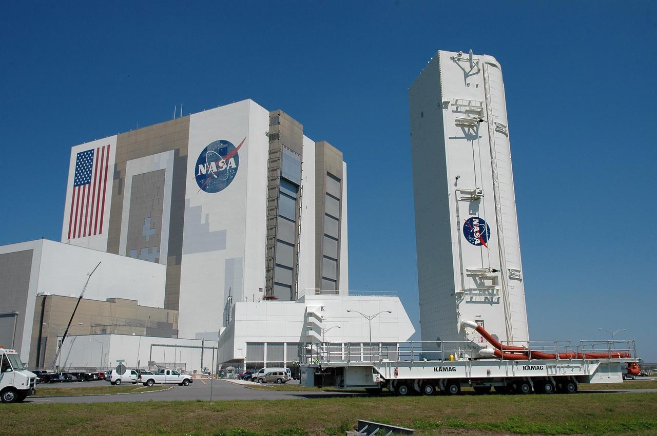 KENNEDY SPACE CENTER, FLA. --    The payload canister passes NASA's Vehicle Assembly Building and Launch Control Center on its way to Launch Pad 39B.  Inside are the payloads for mission STS-121: the multi-purpose logistics module Leonardo, with supplies and equipment for the International Space Station; the lightweight multi-purpose experiment support structure carrier; and the integrated cargo carrier, with the mobile transporter reel assembly and a spare pump module. The payload will be transferred from the canister to Space Shuttle Discovery's payload bay at the pad.  Discovery is scheduled to launch on mission STS-121 from Launch Pad 39B in a window that opens July 1 and extends to July 19.  Photo credit: NASA/Kim Shiflett