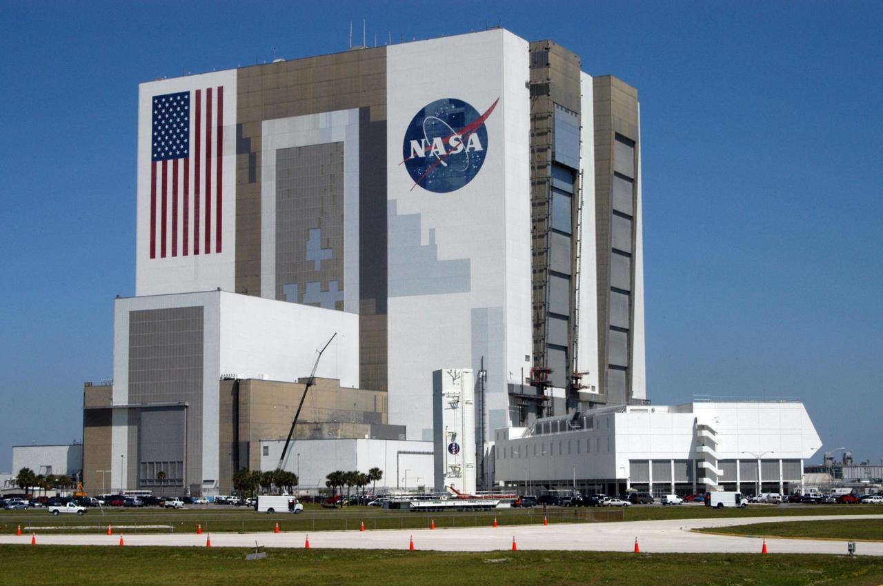 KENNEDY SPACE CENTER, FLA. --    The payload canister passes NASA's Vehicle Assembly Building and Launch Control Center on its way to Launch Pad 39B.  Inside are the payloads for mission STS-121: the multi-purpose logistics module Leonardo, with supplies and equipment for the International Space Station; the lightweight multi-purpose experiment support structure carrier; and the integrated cargo carrier, with the mobile transporter reel assembly and a spare pump module. The payload will be transferred from the canister to Space Shuttle Discovery's payload bay at the pad.  Discovery is scheduled to launch on mission STS-121 from Launch Pad 39B in a window that opens July 1 and extends to July 19.  Photo credit: NASA/George Shelton