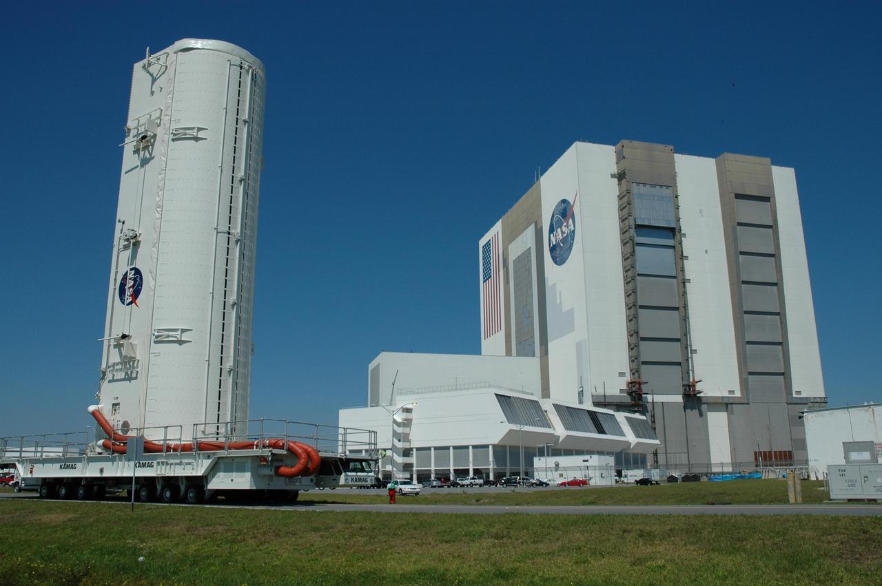 KENNEDY SPACE CENTER, FLA. --   The payload canister passes NASA's Vehicle Assembly Building and Launch Control Center on its way to Launch Pad 39B.  Inside are the payloads for mission STS-121: the multi-purpose logistics module Leonardo, with supplies and equipment for the International Space Station; the lightweight multi-purpose experiment support structure carrier; and the integrated cargo carrier, with the mobile transporter reel assembly and a spare pump module. The payload will be transferred from the canister to Space Shuttle Discovery's payload bay at the pad.  Discovery is scheduled to launch on mission STS-121 from Launch Pad 39B in a window that opens July 1 and extends to July 19. Photo credit: NASA/Troy Cryder