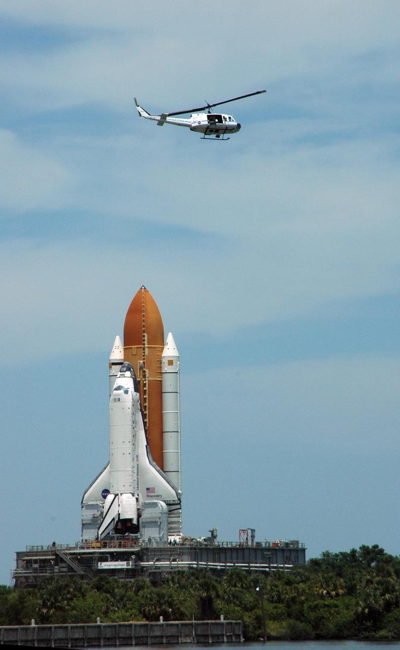 KENNEDY SPACE CENTER, FLA. -- A NASA helicopter follows the route of Space Shuttle Discovery on the crawlerway as it rolls out toward Launch Pad 39B. First motion of the shuttle from NASA's Vehicle Assembly Building was at 12:45 p.m. EDT. The rollout is an important step before launch of Discovery on mission STS-121 to the International Space Station. Discovery's launch is targeted for July 1 in a launch window that extends to July 19. During the 12-day mission, Discovery's crew will test new hardware and techniques to improve shuttle safety, as well as deliver supplies and make repairs to the station. Photo credit: NASA/Ken Thornsley