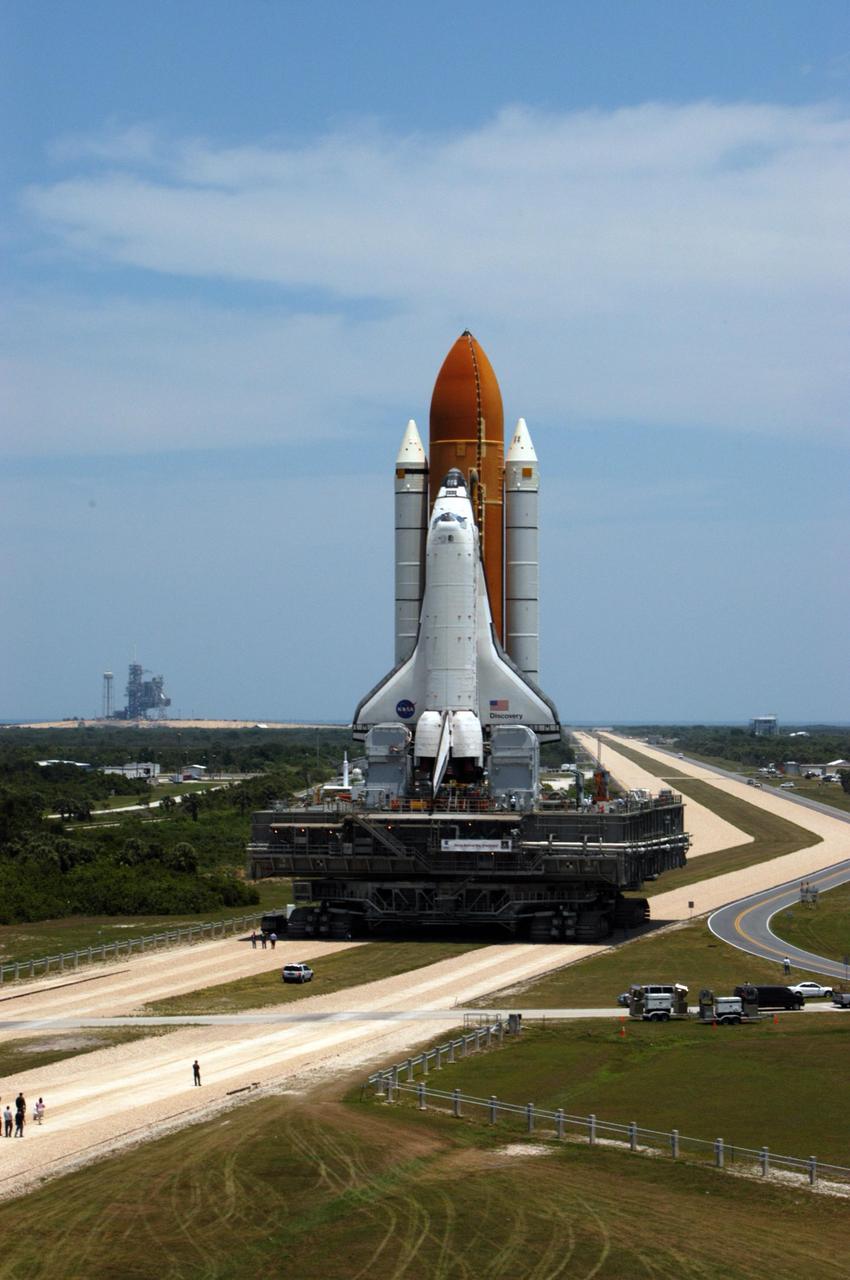 KENNEDY SPACE CENTER, FLA. -- Space Shuttle Discovery rolls toward Launch Pad 39B. Launch Pad 39A is in the background. The shuttle rests on a mobile launcher platform that sits atop a crawler-transporter. First motion from NASA's Vehicle Assembly Building was at 12:45 p.m. EDT. The rollout is an important step before launch of Discovery on mission STS-121 to the International Space Station. Discovery's launch is targeted for July 1 in a launch window that extends to July 19. During the 12-day mission, Discovery's crew will test new hardware and techniques to improve shuttle safety, as well as deliver supplies and make repairs to the station. Photo credit: NASA/George Shelton
