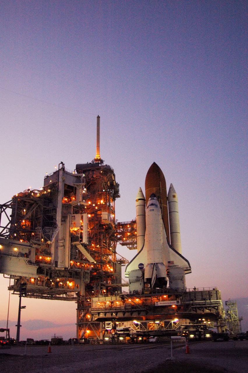 KENNEDY SPACE CENTER, FLA. -- Amid the glow of lights from the fixed and rotating service structures, Space Shuttle Discovery rests on the hardstand of Launch Pad 39B at NASA's Kennedy Space Center after completing the 4.2-mile journey from the Vehicle Assembly Building. First motion was at 12:45 p.m. EDT. The shuttle rests on a mobile launcher platform. The rollout is an important step before launch of Discovery on mission STS-121 to the International Space Station. First motion of the shuttle leaving NASA's Vehicle Assembly Building was at 12:45 p.m. EDT. Discovery's launch is targeted for July 1 in a launch window that extends to July 19. During the 12-day mission, Discovery's crew will test new hardware and techniques to improve shuttle safety, as well as deliver supplies and make repairs to the station. Photo credit: NASA/Ken Thornsley