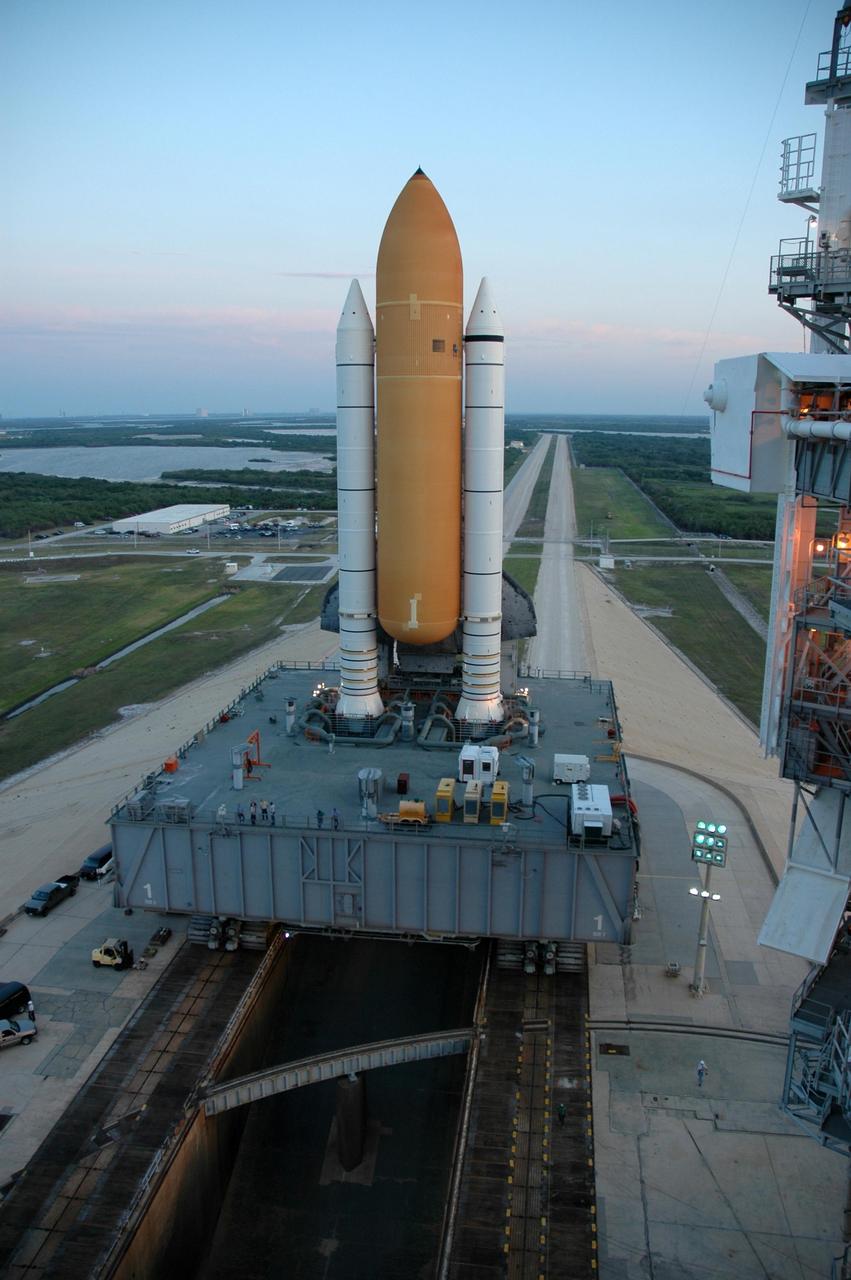 KENNEDY SPACE CENTER, FLA. --  Space Shuttle Discovery, seen behind the orange external tank and white solid rocket boosters, moves into place on the hardstand of Launch Pad 39B.  The shuttle rests on a mobile launcher platform and made the 4.2-mile journey from the Vehicle Assembly Building via the crawler-transporter beneath the platform.  The rollout is an important step before launch of Discovery on mission STS-121 to the International Space Station.  Discovery's launch is targeted for July 1 in a launch window that extends to July 19. During the 12-day mission, Discovery's crew will test new hardware and techniques to improve shuttle safety, as well as deliver supplies and make repairs to the station. Photo credit: NASA/Dimitri Gerondidakis
