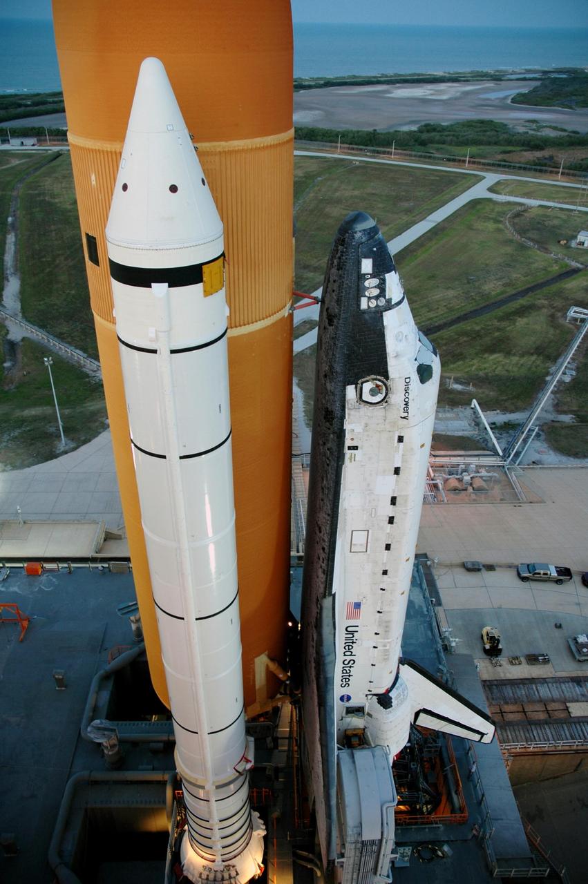 KENNEDY SPACE CENTER, FLA. --   This side view taken from the upper level of the fixed service structure shows Space Shuttle Discovery, mated with the orange external tank, as it has come to rest on the hardstand of Launch Pad 39B.  The shuttle rests on a mobile launcher platform and made the 4.2-mile journey from the Vehicle Assembly Building via the crawler-transporter beneath the platform.  The rollout is an important step before launch of Discovery on mission STS-121 to the International Space Station.  Discovery's launch is targeted for July 1 in a launch window that extends to July 19. During the 12-day mission, Discovery's crew will test new hardware and techniques to improve shuttle safety, as well as deliver supplies and make repairs to the station. Photo credit: NASA/Dimitri Gerondidakis