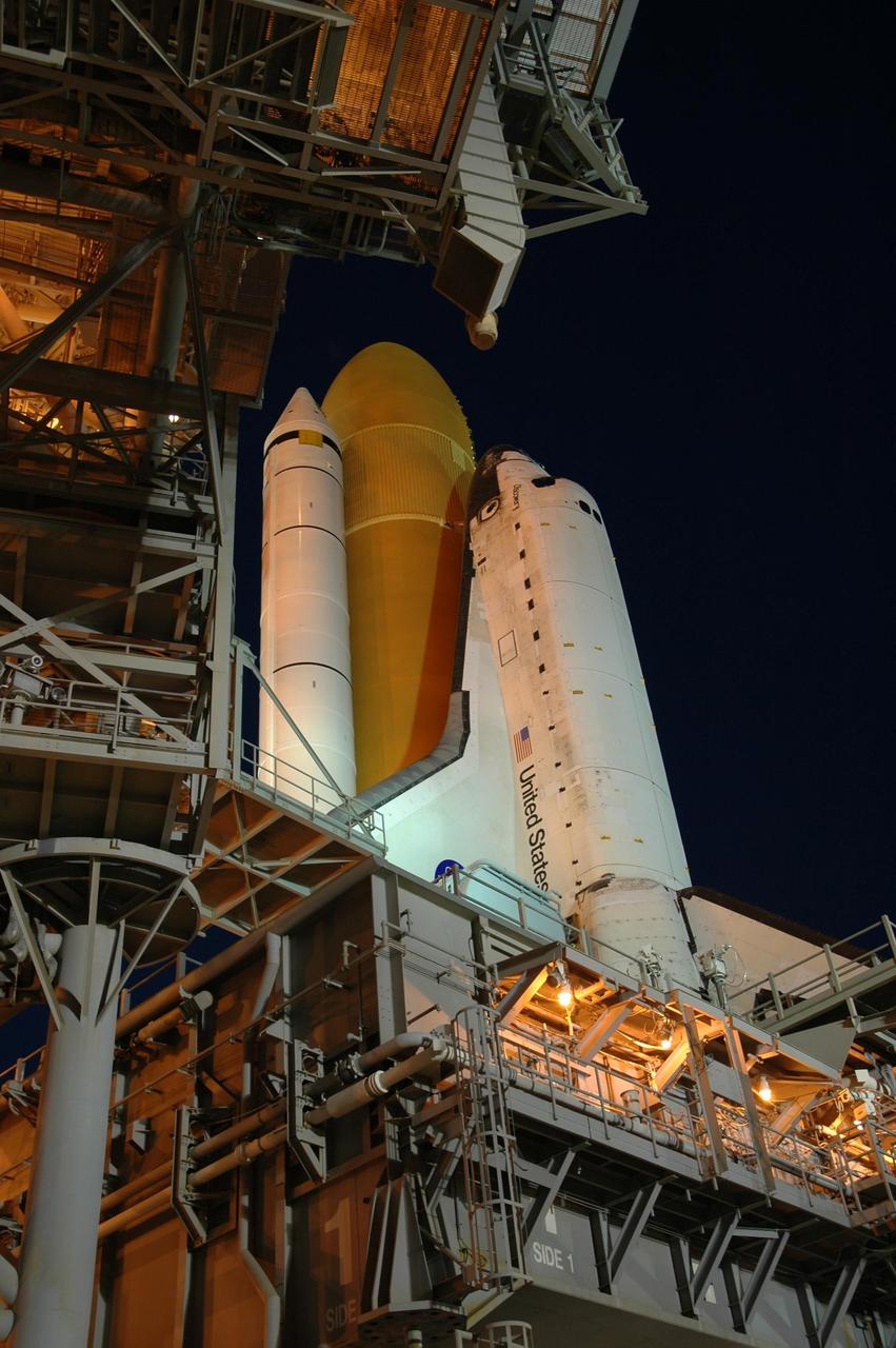 KENNEDY SPACE CENTER, FLA. --   Amid the glow of lights from the fixed and rotating service structures, Space Shuttle Discovery rests on the hardstand of Launch Pad 39B at NASA's Kennedy Space Center after completing the 4.2-mile journey from the Vehicle Assembly Building. First motion was at 12:45 p.m. EDT. The shuttle rests on a mobile launcher platform.  The rollout is an important step before launch of Discovery on mission STS-121 to the International Space Station.  Discovery's launch is targeted for July 1 in a launch window that extends to July 19. During the 12-day mission, Discovery's crew will test new hardware and techniques to improve shuttle safety, as well as deliver supplies and make repairs to the station. Photo credit: NASA/Dimitri Gerondidakis
