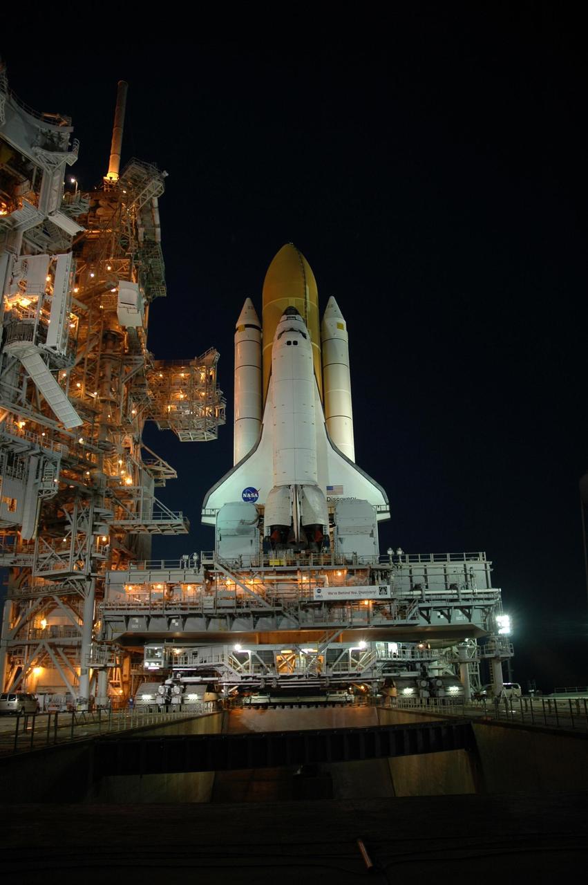 KENNEDY SPACE CENTER, FLA. --   The lights from the fixed and rotating service structures bathe Space Shuttle Discovery in a warm glow as it rests on the hardstand of Launch Pad 39B at NASA's Kennedy Space Center after completing the 4.2-mile journey from the Vehicle Assembly Building. First motion was at 12:45 p.m. EDT. The shuttle rests on a mobile launcher platform.  The rollout is an important step before launch of Discovery on mission STS-121 to the International Space Station.  Discovery's launch is targeted for July 1 in a launch window that extends to July 19. During the 12-day mission, Discovery's crew will test new hardware and techniques to improve shuttle safety, as well as deliver supplies and make repairs to the station. Photo credit: NASA/Dimitri Gerondidakis