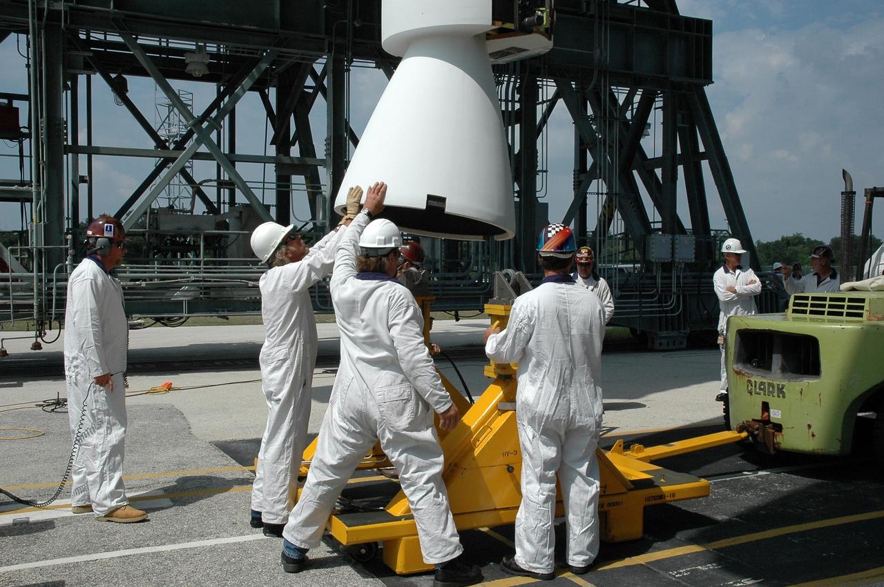 KENNEDY SPACE CENTER, FLA. - Workers on Launch Pad 17-B at Cape Canaveral Air Force Station help guide a solid rocket booster being lifted into the mobile service tower. The booster will be mated with the Boeing Delta II rocket already in place. The Delta rocket is the launch vehicle for NASA's Solar Terrestrial Relations Observatory (STEREO). Preparations are under way for a liftoff no earlier than July 22. STEREO consists of two spacecraft whose mission is the first to take measurements of the sun and solar wind in 3-D. This new view will improve our understanding of space weather and its impact on the Earth. Photo credit: NASA/Jack Pfaller