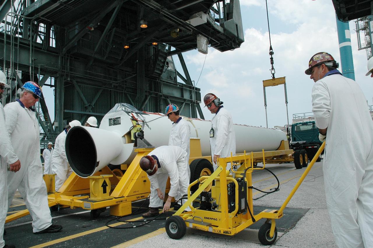 KENNEDY SPACE CENTER, FLA. - Workers get ready to raise a solid rocket booster off its transporter on Launch Pad 17-B at Cape Canaveral Air Force Station. It will be lifted into the mobile service tower above and mated with the Boeing Delta II rocket already in place. The Delta rocket is the launch vehicle for NASA's Solar Terrestrial Relations Observatory (STEREO). Preparations are under way for a liftoff no earlier than July 22. STEREO consists of two spacecraft whose mission is the first to take measurements of the sun and solar wind in 3-D. This new view will improve our understanding of space weather and its impact on the Earth. Photo credit: NASA/Jack Pfaller