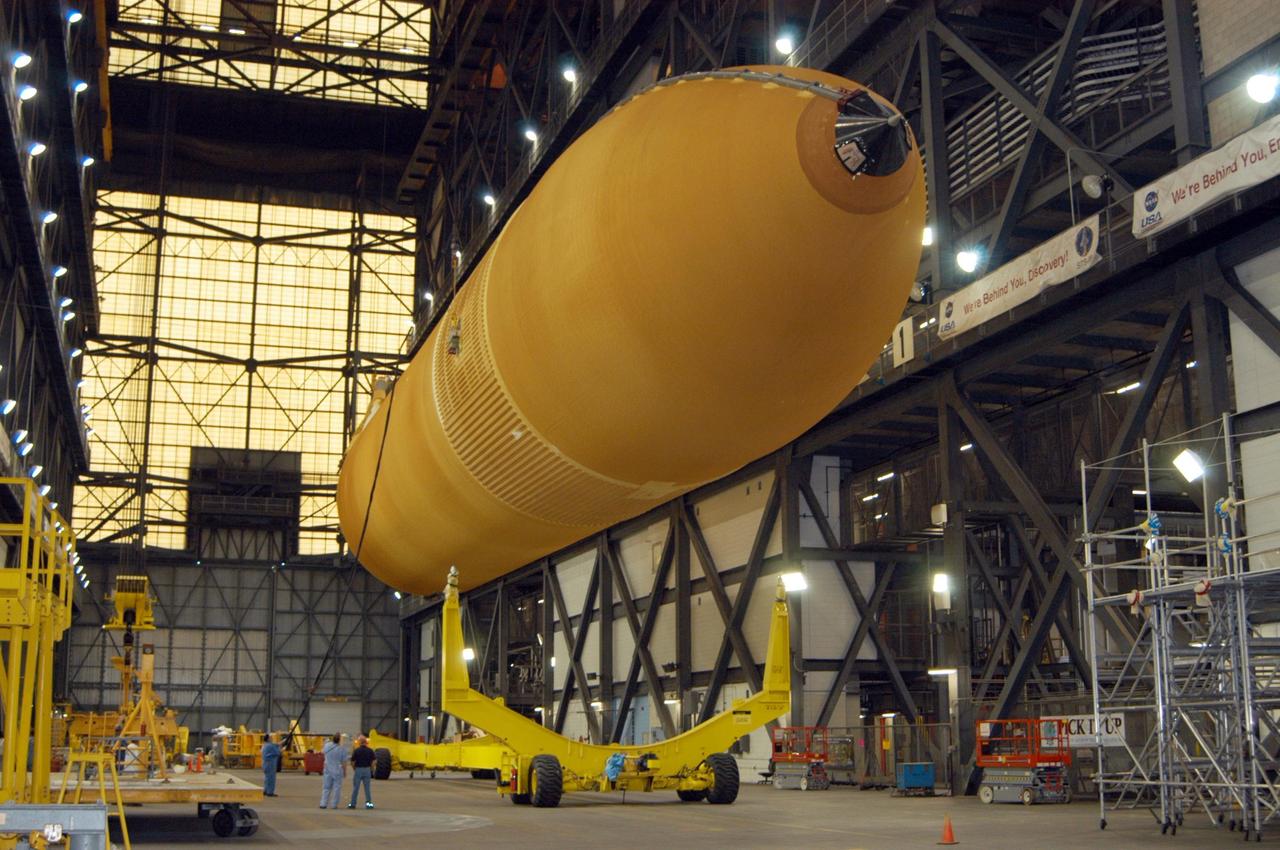 KENNEDY SPACE CENTER, FLA. - In the transfer aisle of NASA's Vehicle Assembly Building, the redesigned external fuel tank that will launch Space Shuttle Atlantis on the next shuttle mission, STS-115, is lifted off its transporter and will be raised to a vertical position. Once it is raised, the tank will be moved into a checkout cell for further work. The tank, designated ET-118, will fly with many major safety changes, including the removal of the protuberance air load ramps. Photo credit: NASA/George Shelton