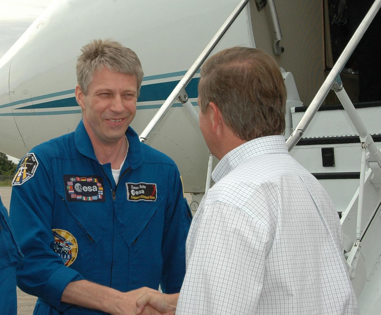 KENNEDY SPACE CENTER, FLA. - During a break in the rain storms from Tropical Storm Alberto, the STS-121 crew arrives at NASA's Kennedy Space Center aboard a Grumman G2 aircraft to take part in a Terminal Countdown Demonstration Test, or TCDT. Greeting the crew is Shuttle Launch Director Mike Leinbach, here shaking hands with Mission Specialist Thomas Reiter, who represents the European Space Agency.  Other crew members are Mission Commander Steven Lindsey, Pilot Mark Kelly, and Mission Specialists Piers Sellers, Michael Fossum, Lisa Nowak and Stephanie Wilson. Over several days, the crew will practice emergency egress from the pad and suit up in their orange flight suits for the simulated countdown to launch. Space Shuttle Discovery is designated to launch July 1 on mission STS-121.  It will carry supplies to the International Space Station.  Photo credit: NASA/Kim Shiflett