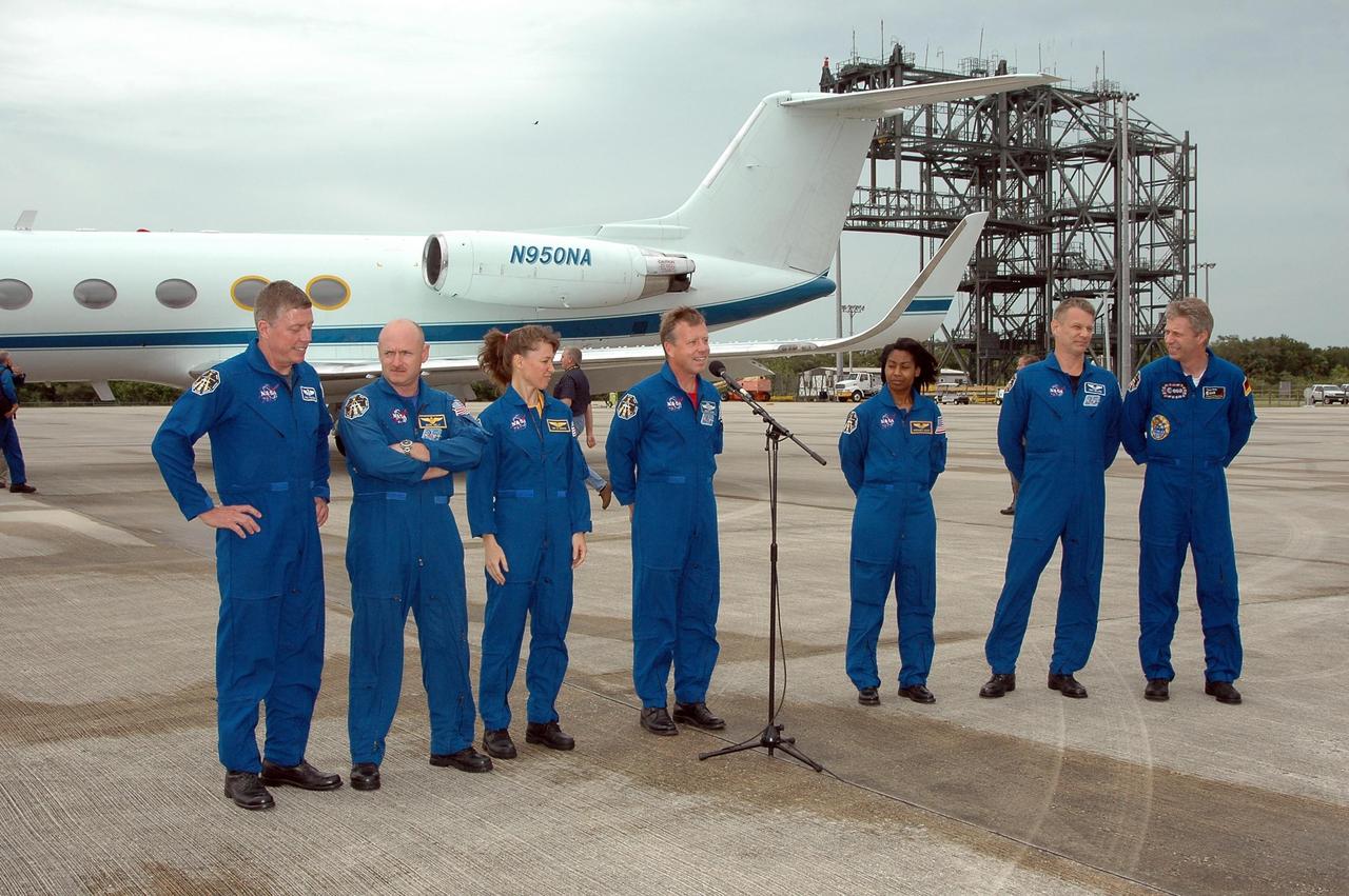 KENNEDY SPACE CENTER, FLA. - After landing at NASA's Kennedy Space Center aboard a Grumman G2 aircraft, the STS-121 crew gathers at a microphone for the media.  Mission Commander Steven Lindsey is introducing the crew, from left: Mission Specialist Michael Fossum, Pilot Mark Kelly, Mission Specialist Lisa Nowak, Lindsey, Mission Specialists Stephanie Wilson, Piers Sellers and Thomas Reiter, who represents the European Space Agency.  The crew is at the space center to take part in a Terminal Countdown Demonstration Test, or TCDT. Over several days, the crew will practice emergency egress from the pad and suit up in their orange flight suits for the simulated countdown to launch. Space Shuttle Discovery is designated to launch July 1 on mission STS-121.  It will carry supplies to the International Space Station.  Photo credit: NASA/Kim Shiflett