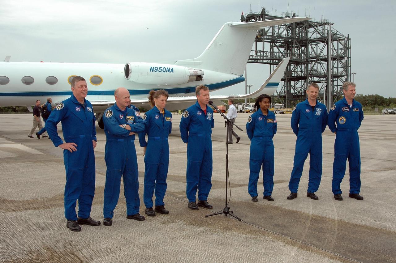 KENNEDY SPACE CENTER, FLA. - After landing at NASA's Kennedy Space Center aboard a Grumman G2 aircraft, Mission Commander Steven Lindsey pauses at a microphone to introduce the crew.  Joining him are Mission Specialist Michael Fossum, Pilot Mark Kelly, and Mission Specialists Lisa Nowak (partly visible at left), Stephanie Wilson, Piers Sellers and Thomas Reiter, who represents the European Space Agency.   The crew is at the space center to take part in a Terminal Countdown Demonstration Test, or TCDT. Over several days, the crew will practice emergency egress from the pad and suit up in their orange flight suits for the simulated countdown to launch. Space Shuttle Discovery is designated to launch July 1 on mission STS-121.  It will carry supplies to the International Space Station.  Photo credit: NASA/Kim Shiflett