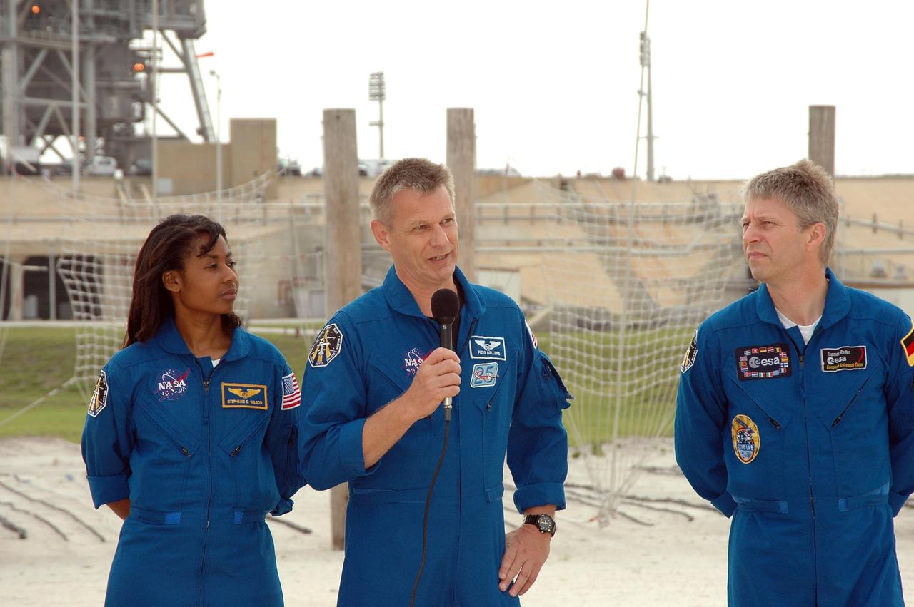KENNEDY SPACE CENTER, FLA. - During a pause in their prelaunch activities at the pad, the STS-121 crew talk to the media. They are standing in the landing area of the slidewire baskets. With the microphone is Mission Specialist Piers Sellers. Next to him are Mission Specialists Stephanie Wilson and Thomas Reiter of Germany, who represents the European Space Agency. The crew is at Kennedy for Terminal Countdown Demonstration Test activities. Over several days, the crew will practice emergency egress from the pad and suit up in their orange flight suits for the simulated countdown to launch. Space Shuttle Discovery is designated to launch July 1 on mission STS-121. It will carry supplies to the International Space Station. Photo credit: NASA/Kim Shiflett