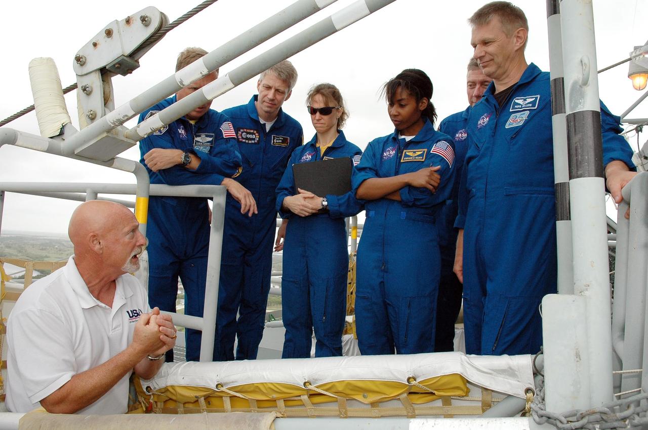 KENNEDY SPACE CENTER, FLA. - The STS-121 crew listens to instructions on emergency egress from the pad. The crew members are (from left) Pilot Mark Kelly, Mission Specialists Piers Sellers, Lisa Nowak, Stephanie Wilson and Thomas Reiter, Commander Steven Lindsey, and Mission Specialist Michael Fossum. Reiter is from Germany and represents the European Space Agency. The crew is at Kennedy for Terminal Countdown Demonstration Test activities, including emergency egress training from the pad. They will also suit up in their orange flight suits for a simulated countdown to launch. Discovery is designated to launch July 1 on mission STS-121. It will carry supplies to the International Space Station. Photo credit: NASA/Kim Shiflett