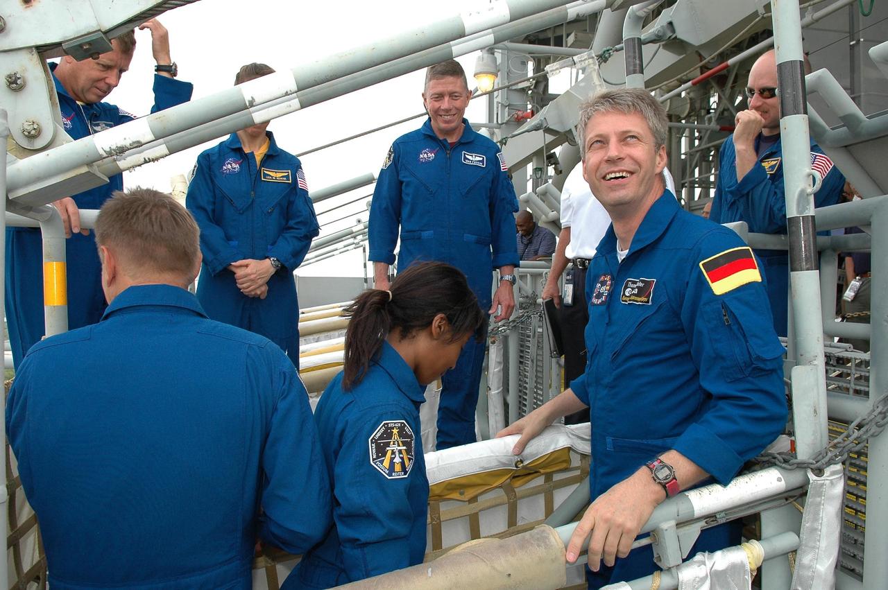 KENNEDY SPACE CENTER, FLA. -  Some of the STS-121 crew practices getting into a slidewire basket on Launch Pad 39B while others watch.  In the basket are Mission Specialists Piers Sellers, Stephanie Wilson and Thomas Reiter.  Behind them are Commander Steven Lindsey, Mission Specialists Lisa Nowak and Michael Fossum, and Pilot Mark Kelly. The crew is at Kennedy for Terminal Countdown Demonstration Test activities, including emergency egress training from the pad.  They will also suit up in their orange flight suits for a simulated countdown to launch. Discovery is designated to launch July 1 on mission STS-121.  It will carry supplies to the International Space Station.  Photo credit: NASA/Kim Shiflett