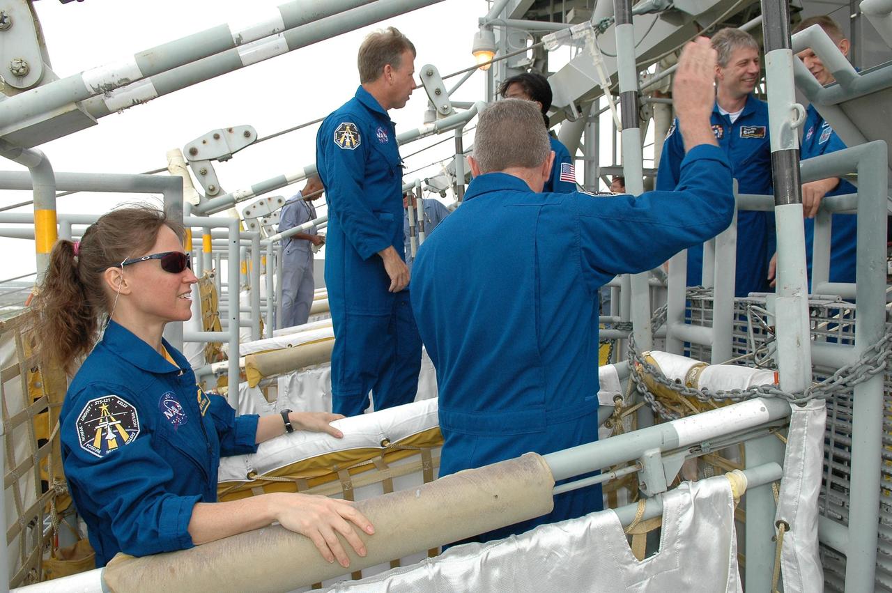 KENNEDY SPACE CENTER, FLA. -  Some of the STS-121 crew practices getting into a slidewire basket on Launch Pad 39B.  At left is Mission Specialist Lisa Nowak; in front of her is Mission Specialist Michael Fossum.  In the background are Commander Steven Lindsey and Mission Specialists Stephanie Wilson, Thomas Reiter and Piers Sellers.  The crew is at Kennedy for Terminal Countdown Demonstration Test activities, including emergency egress training from the pad.  They will also suit up in their orange flight suits for a simulated countdown to launch. Discovery is designated to launch July 1 on mission STS-121.  It will carry supplies to the International Space Station.  Photo credit: NASA/Kim Shiflett