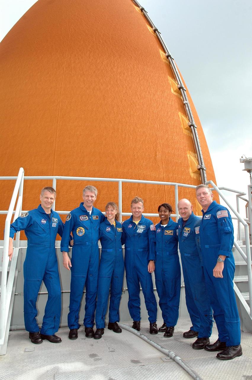 KENNEDY SPACE CENTER, FLA. - During emergency egress training at the pad, the STS-121 crew pose for a photo on the upper level in front of Space Shuttle Discovery's external tank. From left are Mission Specialists Piers Sellers, Thomas Reiter and Lisa Nowak, Commander Steven Lindsey, Mission Specialist Stephanie Wilson, Pilot Mark Kelly and Mission Specialist Michael Fossum. The crew is at Kennedy for Terminal Countdown Demonstration Test activities, including emergency egress training from the pad. They will also suit up in their orange flight suits for a simulated countdown to launch. Discovery is designated to launch July 1 on mission STS-121. It will carry supplies to the International Space Station. Photo credit: NASA/Kim Shiflett