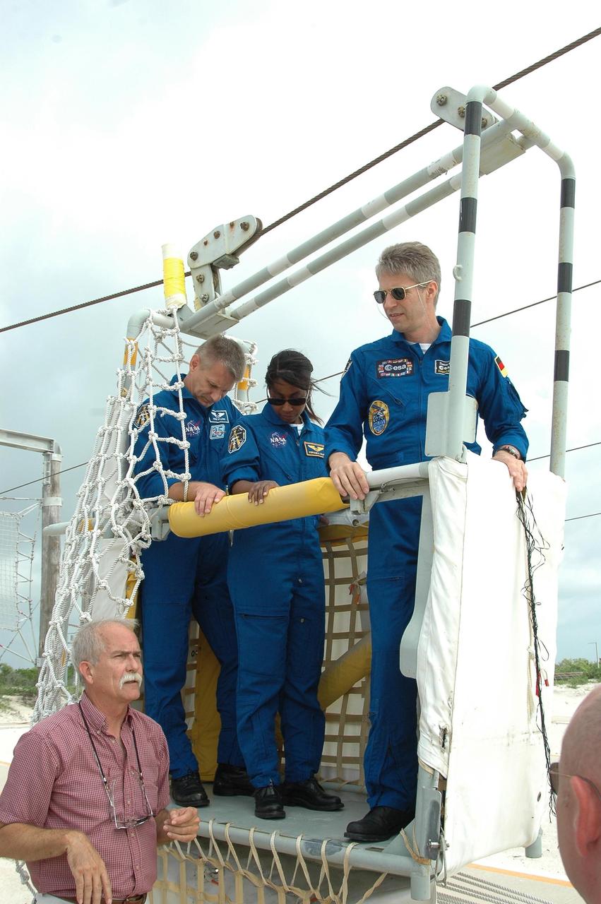 KENNEDY SPACE CENTER, FLA. - During emergency egress training at the pad, STS-121 crew members Piers Sellers, Stephanie Wilson and Thomas Reiter, all mission specialists, learn how to exit the slidewire basket on the ground. The crew is at Kennedy for Terminal Countdown Demonstration Test activities, including emergency egress training from the pad. They will also suit up in their orange flight suits for a simulated countdown to launch. Discovery is designated to launch July 1 on mission STS-121. It will carry supplies to the International Space Station. Photo credit: NASA/Kim Shiflett
