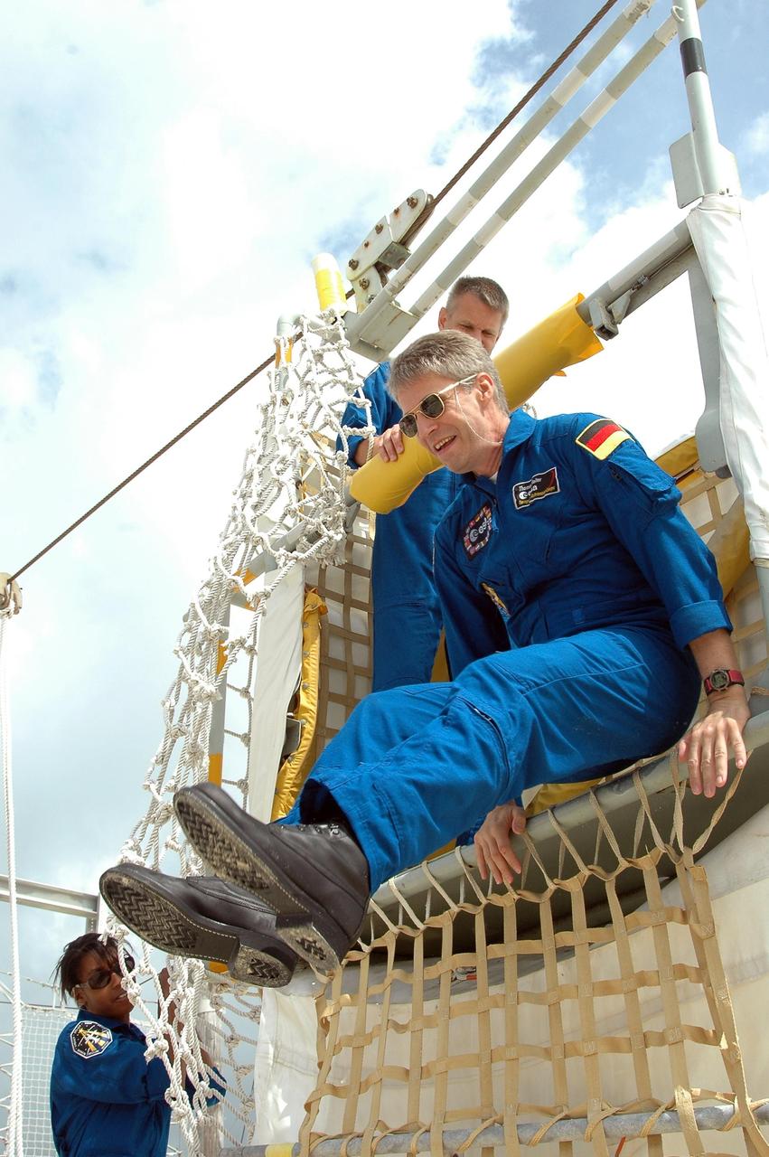 KENNEDY SPACE CENTER, FLA. -  STS-121 Mission Specialist Thomas Reiter prepares to leap from the slidewire basket during training on emergency egress procedures from the launch pad.  Above him is Mission Specialist Piers Sellers; at lower left is Mission Specialist Stephanie Wilson.  The crew is at Kennedy for Terminal Countdown Demonstration Test activities, including emergency egress training from the pad.  They will also suit up in their orange flight suits for a simulated countdown to launch. Discovery is designated to launch July 1 on mission STS-121.  It will carry supplies to the International Space Station.  Photo credit: NASA/Kim Shiflett