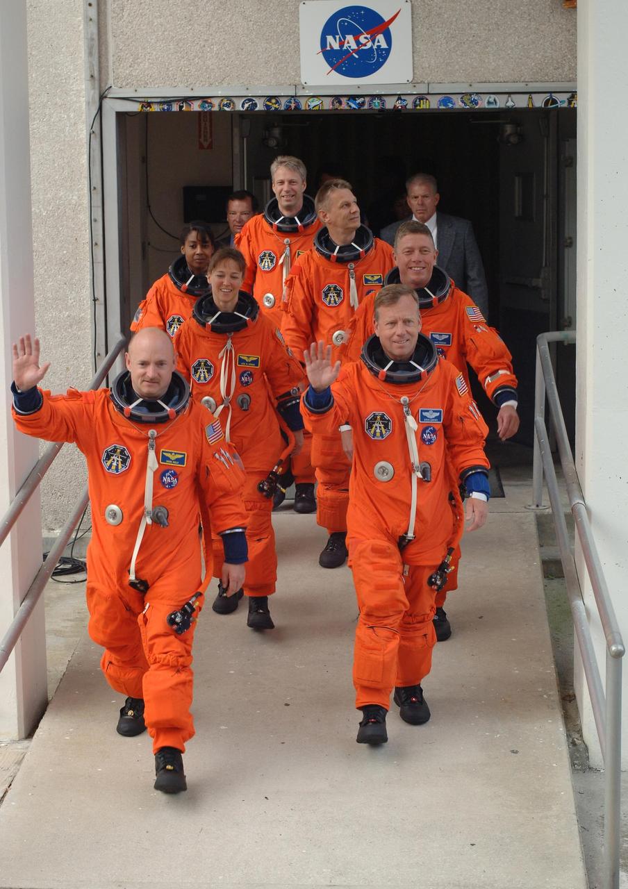 KENNEDY SPACE CENTER, FLA. -  The suited STS-121 crew members stride out of the Operations and Checkout Building on their way to Launch Pad 39B for a simulated countdown. Leading the way are Pilot Mark Kelly (left) and Commander Steven Lindsey.  Behind Kelly are Mission Specialists Lisa Nowak, Stephanie Wilson and Thomas Reiter of Germany, who represents the European Space Agency.  Behind Lindsey are Mission Specialists Michael Fossum and Piers Sellers.   The crew is taking part in Terminal Countdown Demonstration Test activities, including the dress rehearsal for launch. Mission STS-121 is scheduled to be launched July 1.  Photo credit: NASA/Kim Shiflett